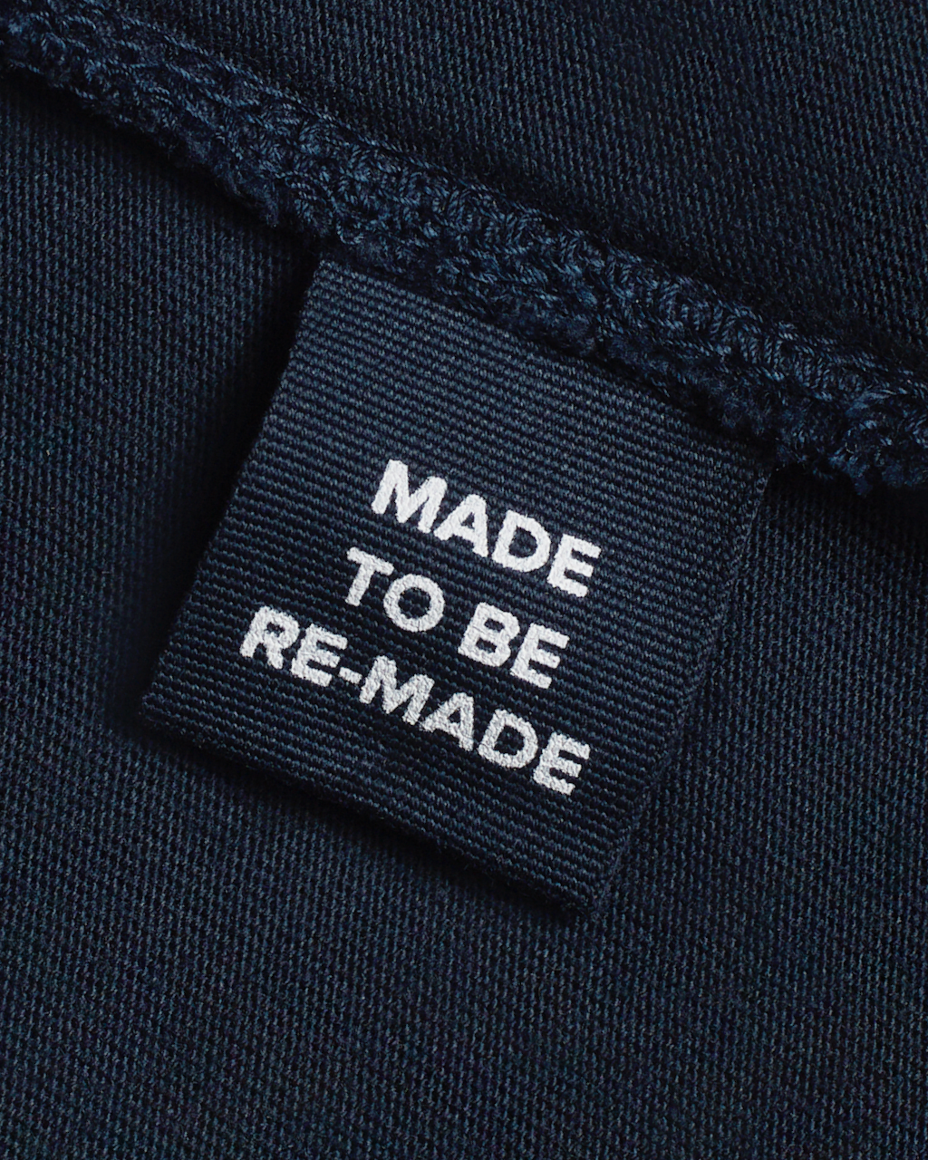 A close up of a label tag in a navy, organic cotton midi skirt that says 'made to be re made'.