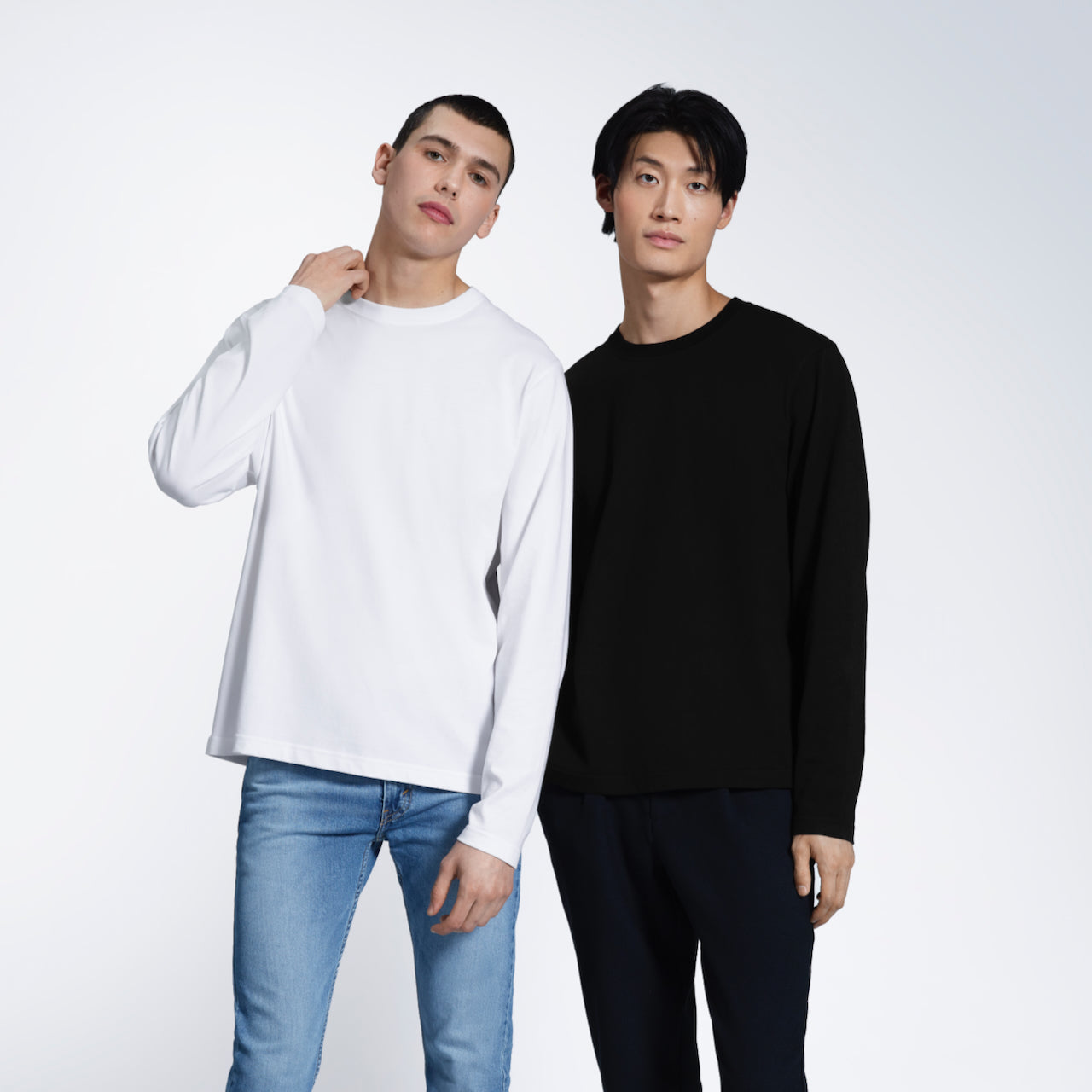 Two men looking into the camera, modelling plain white and black long sleeve organic cotton t shirts.