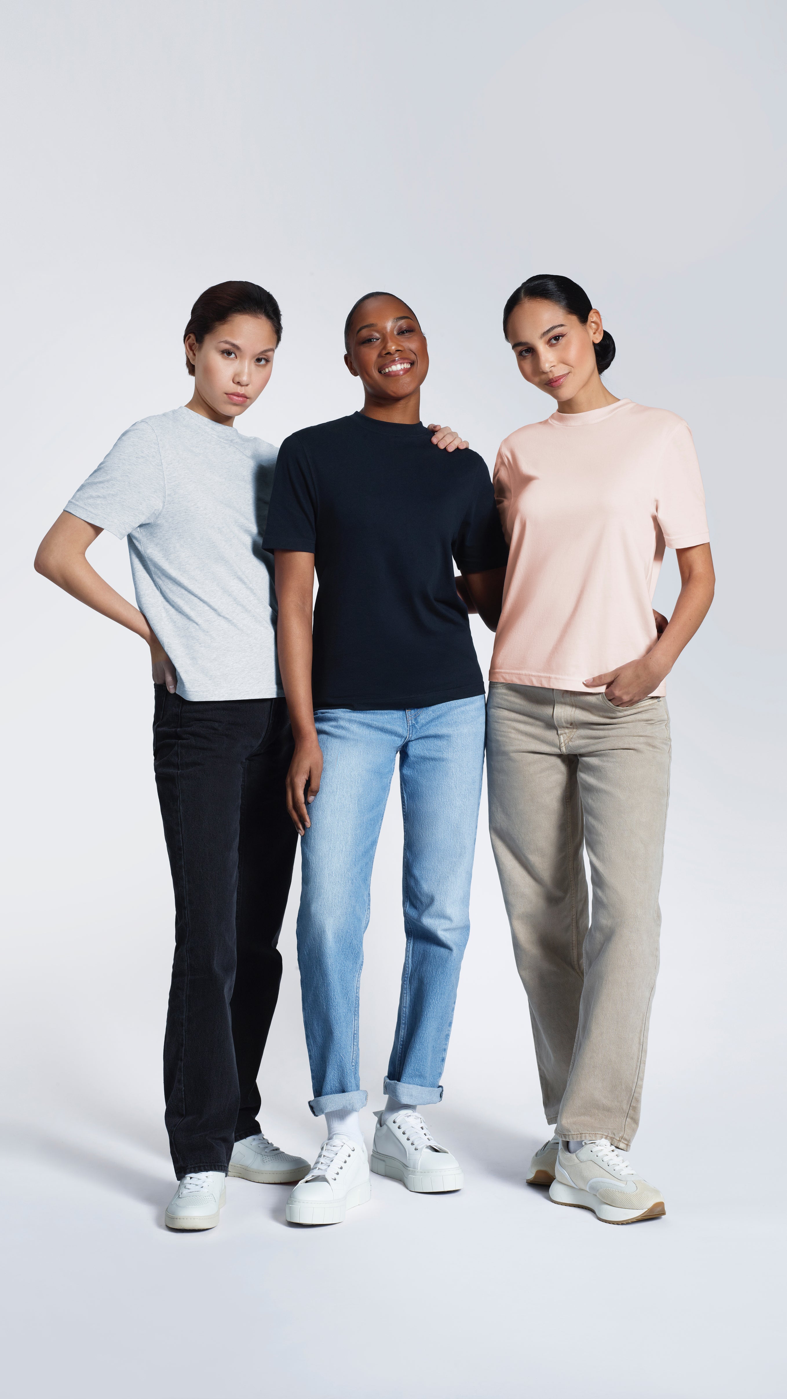 Three women, modelling grey, navy and pink t-shirts.