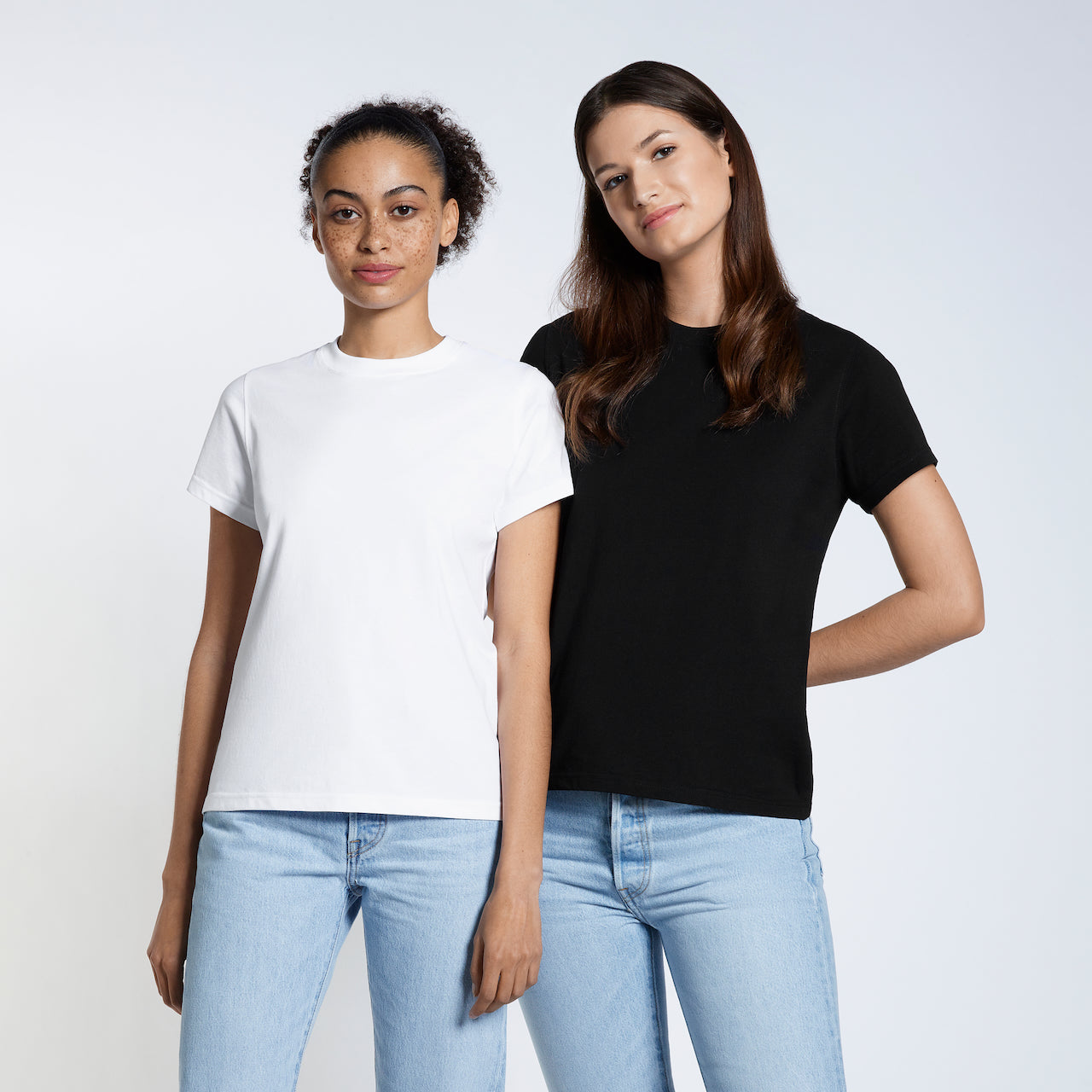 Two women looking at the camera, modelling plain, black and white organic cotton short sleeve t shirts.