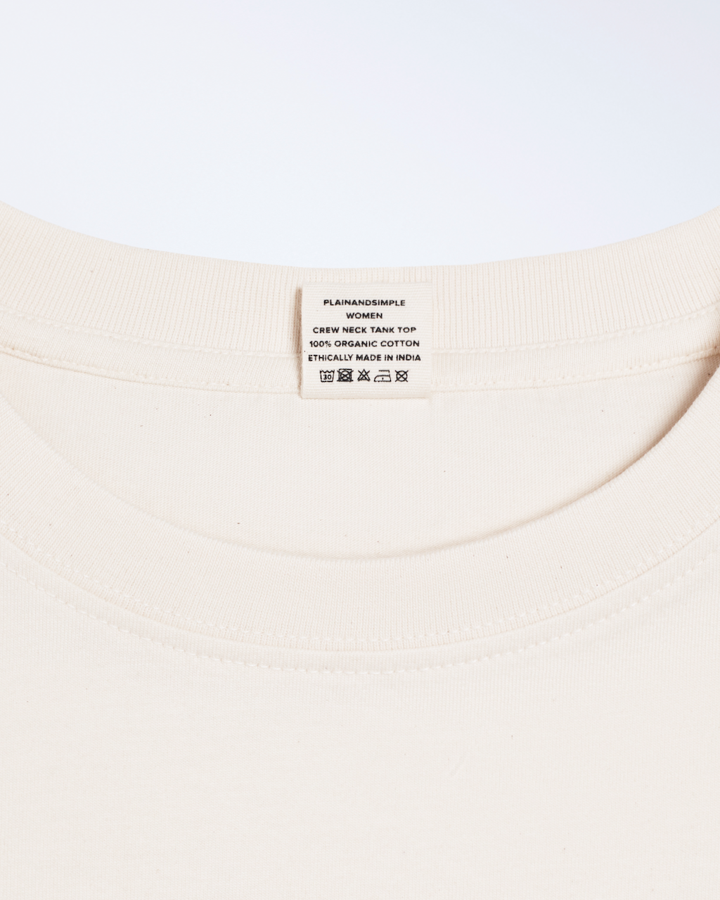 A close up of a neck label, for a natural coloured, crew neck, organic cotton tank top.