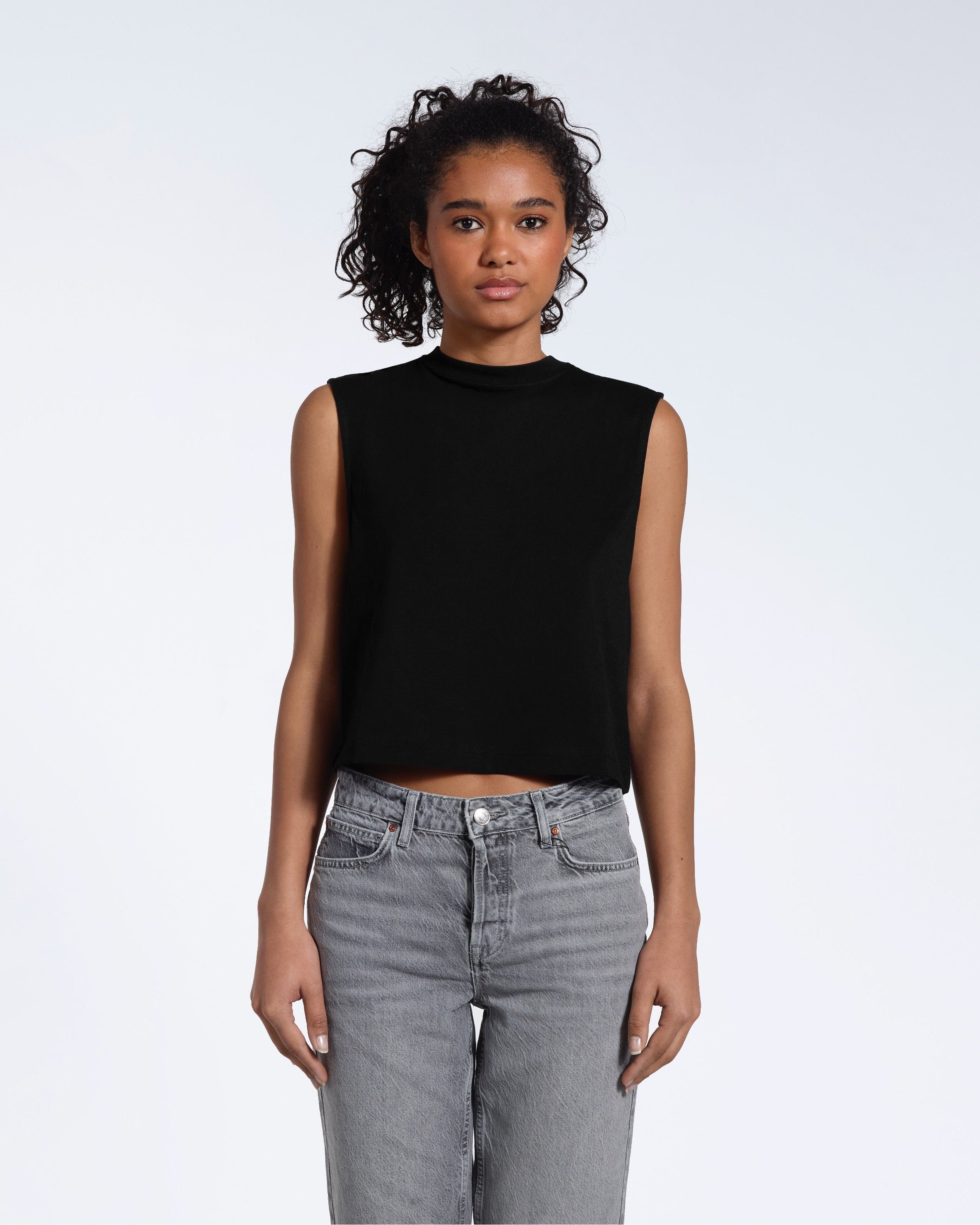 A woman facing front on looking at the camera, modelling a black short sleeve organic cotton tank top.