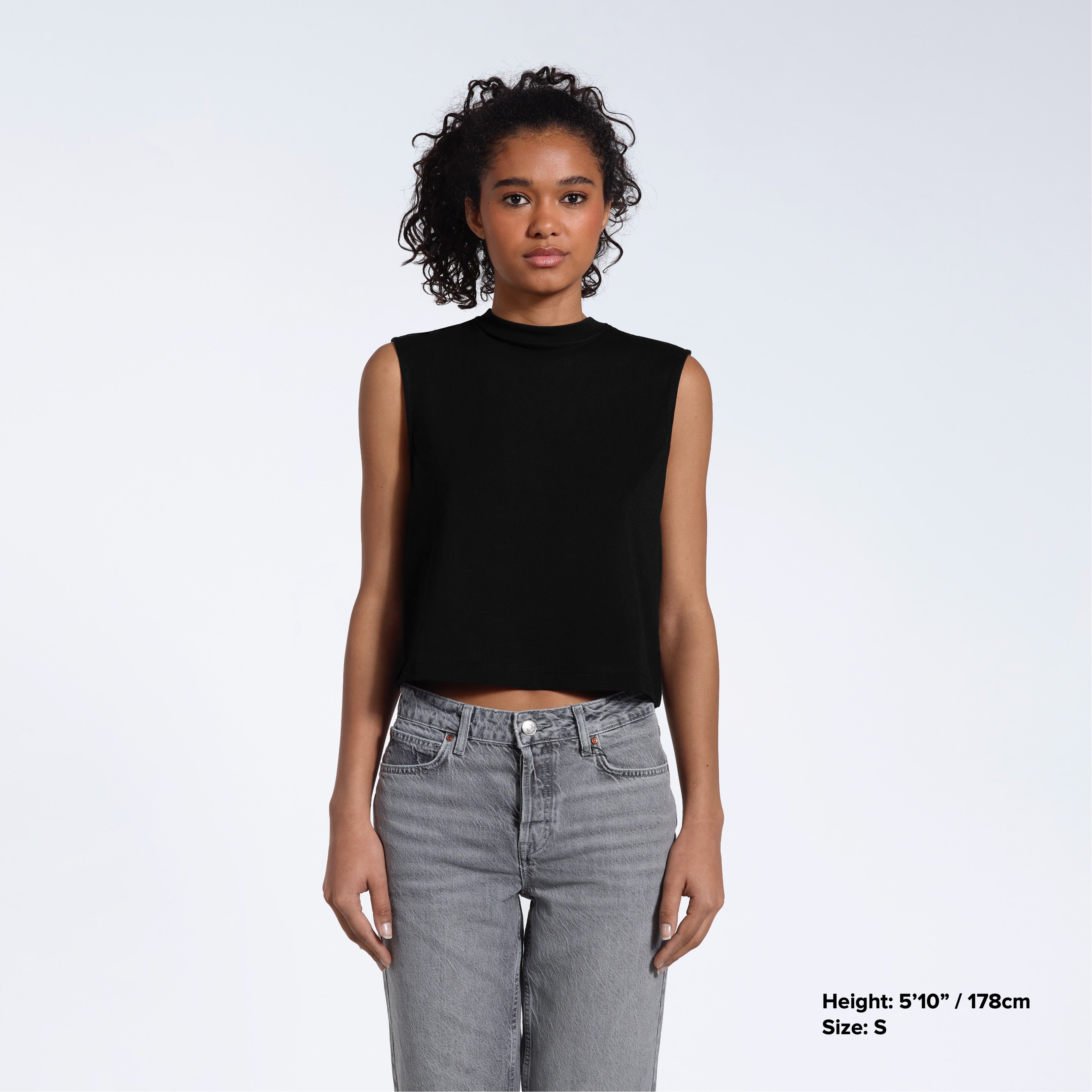 A woman facing front on looking at the camera, modelling a black short sleeve organic cotton tank top.