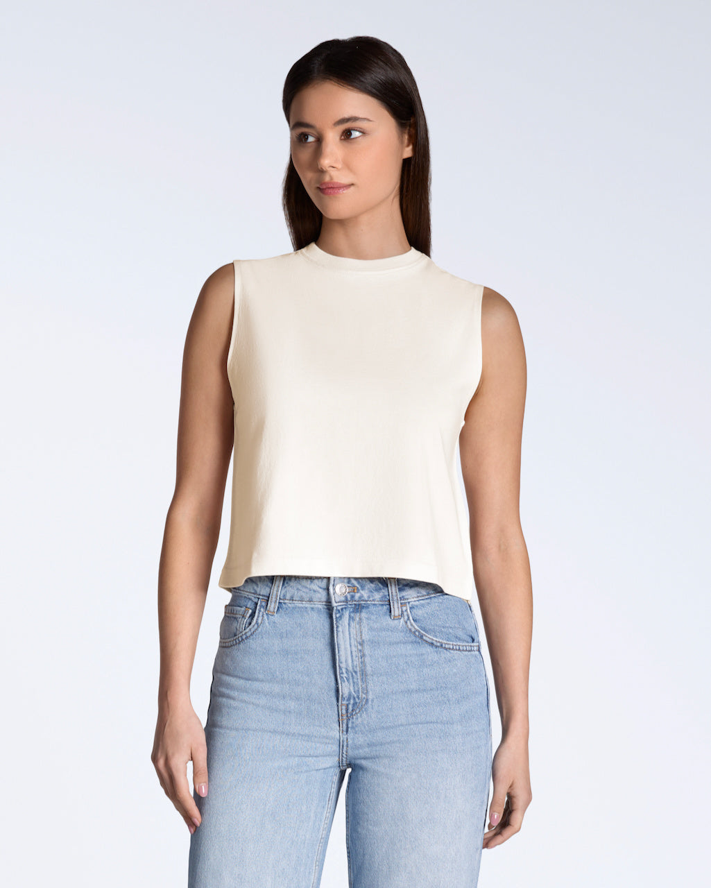 A woman looking away from the camera, modelling a plain natural coloured, organic cotton, crew neck tank top.