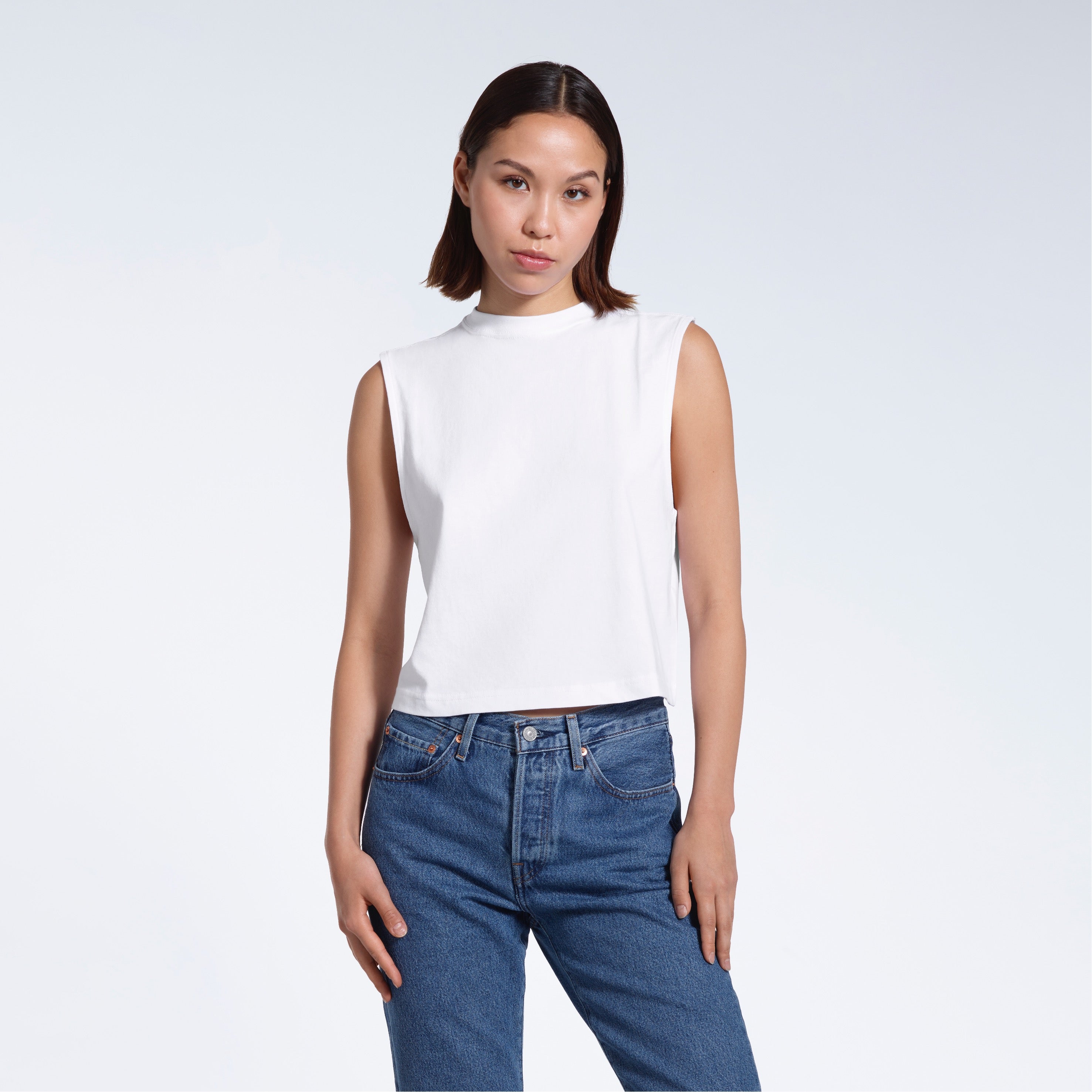 A woman facing front on looking at the camera, modelling a white short sleeve organic cotton tank top.