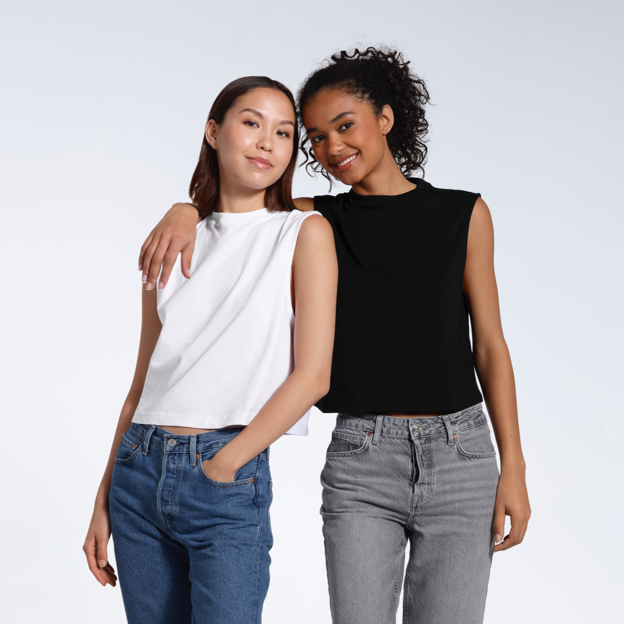Two women smiling looking at the camera, modelling plain black and white organic cotton tank tops.