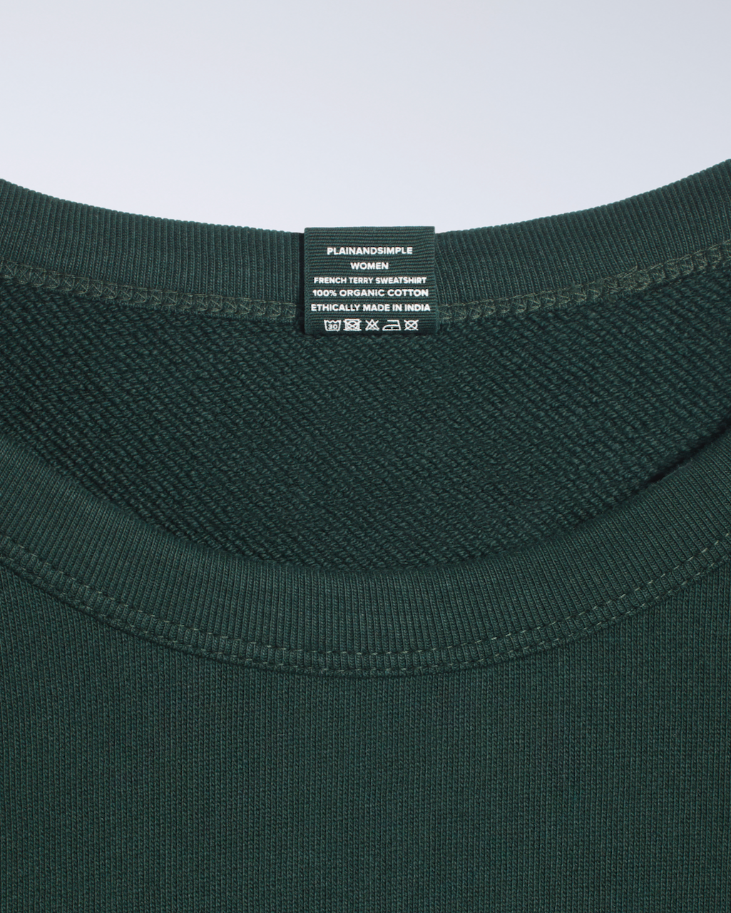 A close up of a neck label in a green, organic cotton sweatshirt.