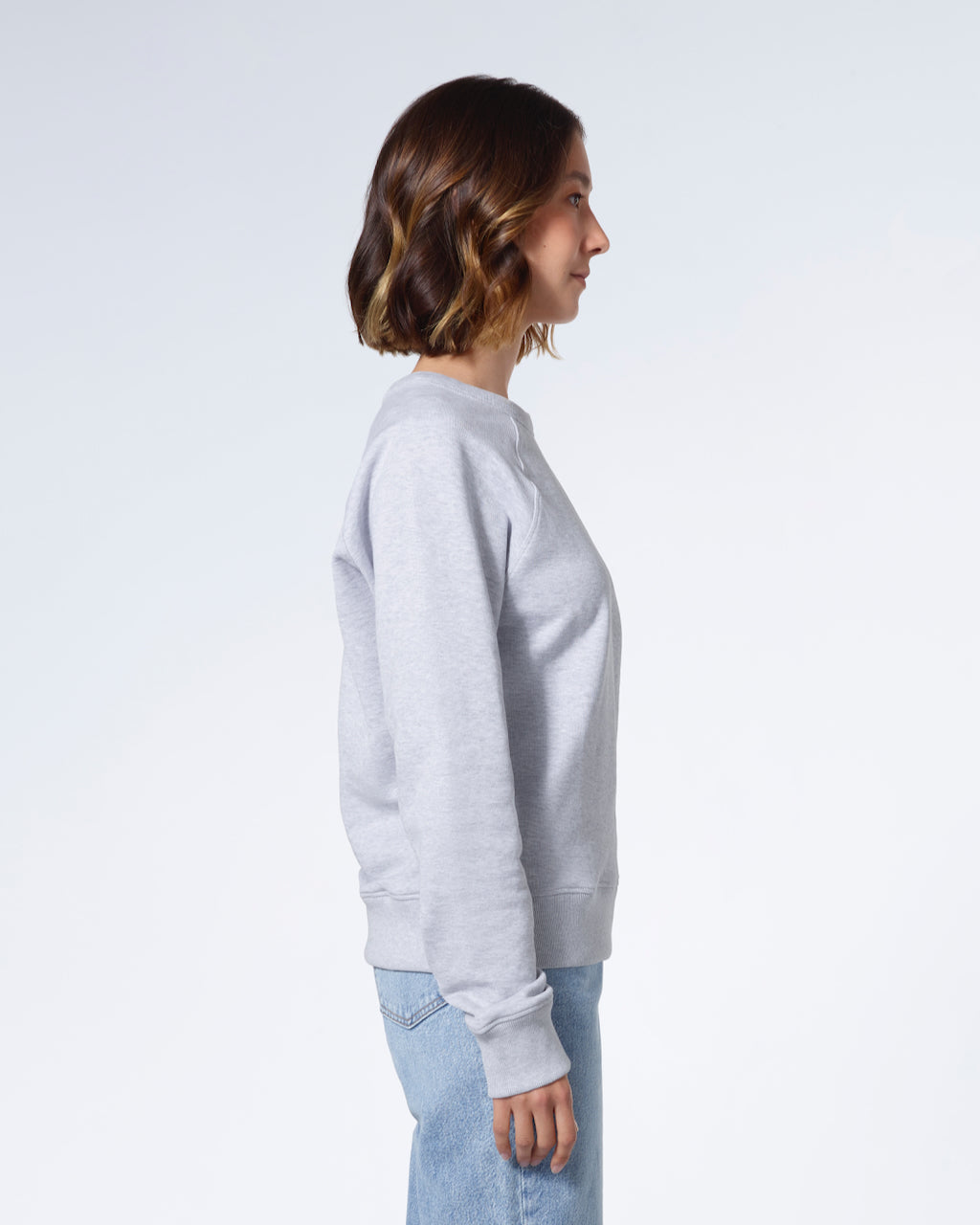 A woman facing side on, modelling a plain grey french terry organic cotton sweatshirt.