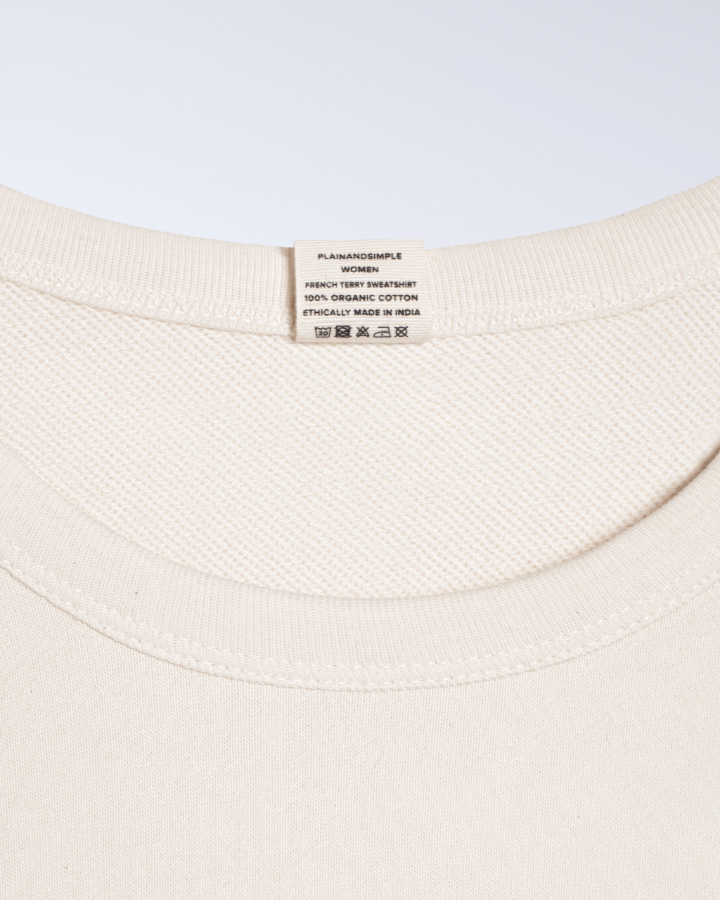 A close up of a neck label in a natural coloured, organic cotton sweatshirt.