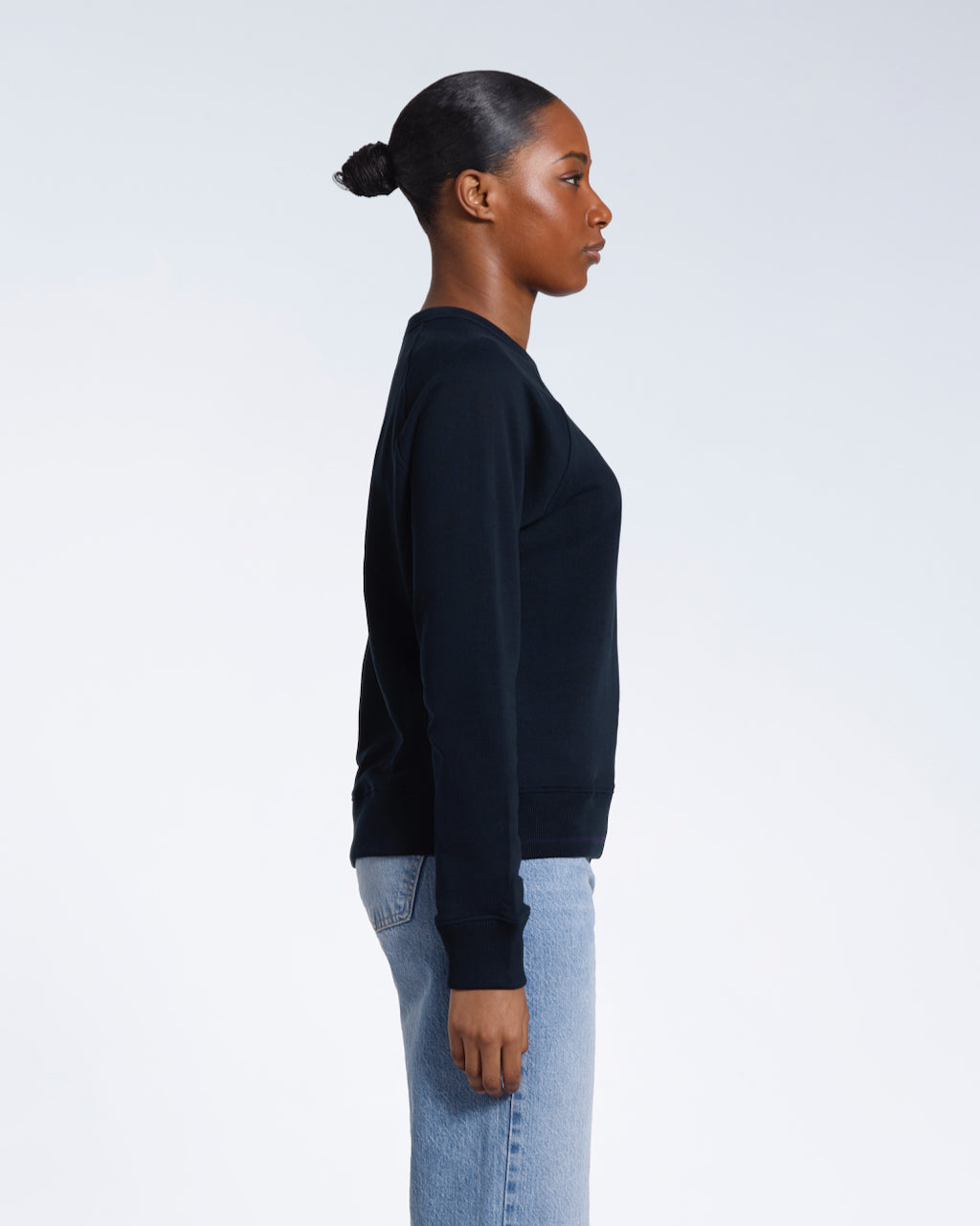 A woman facing side on, modelling a plain navy french terry organic cotton sweatshirt.