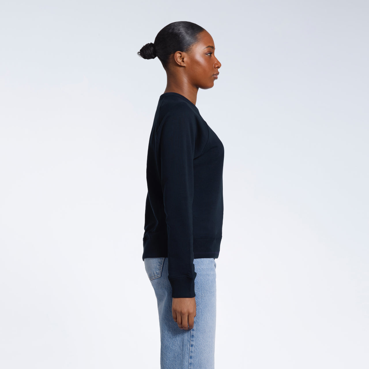 A woman facing side on, modelling a plain navy french terry organic cotton sweatshirt.