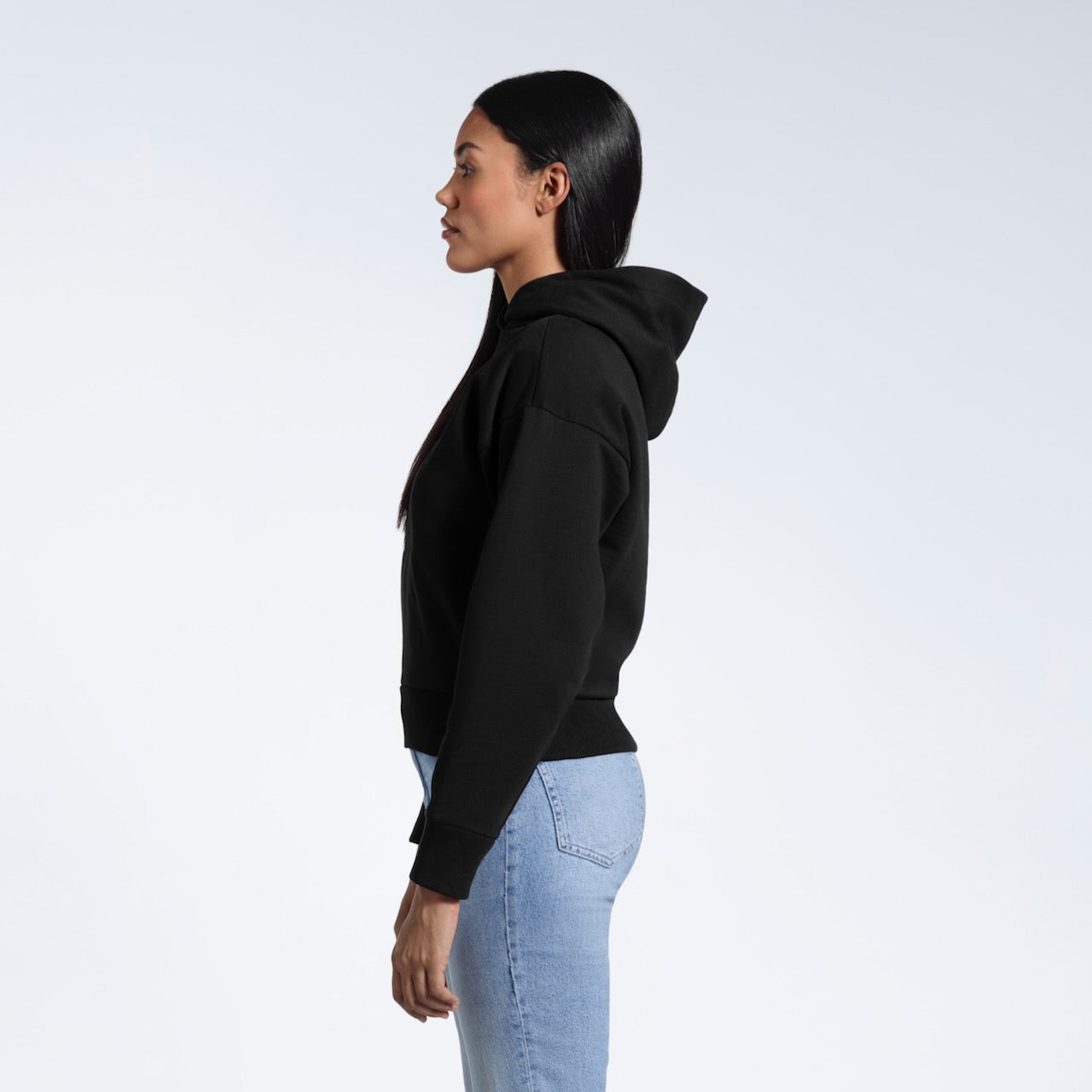 A woman facing side on, modelling a black heavyweight organic cotton hoodie.