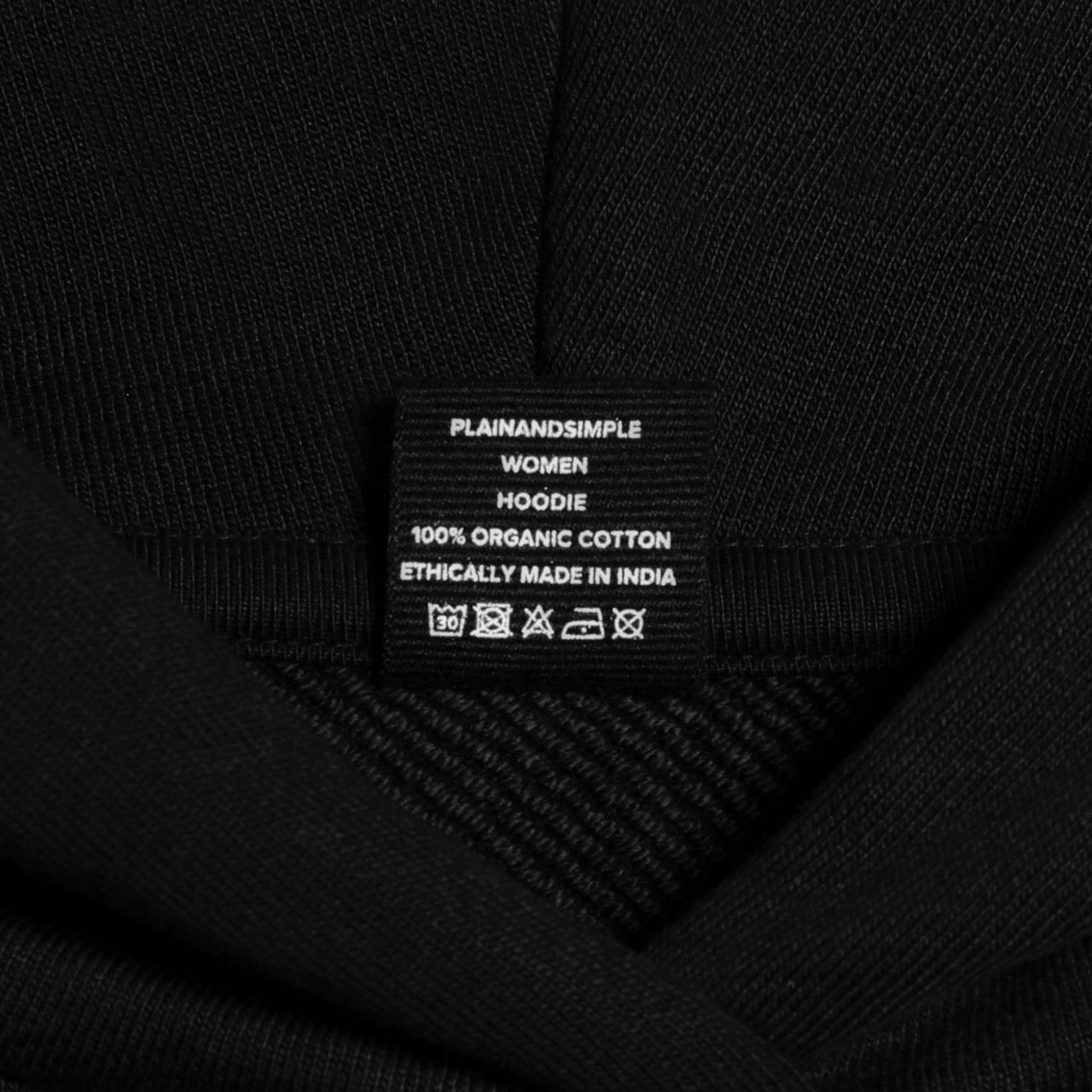 A close up of an neck label in a women's black heavyweight organic cotton hoodie.