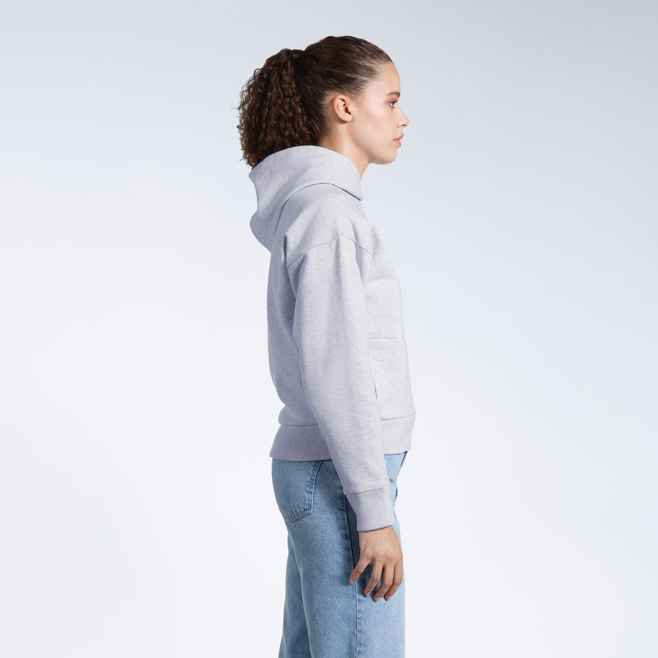 A woman facing side on, modelling a grey heavyweight organic cotton hoodie.