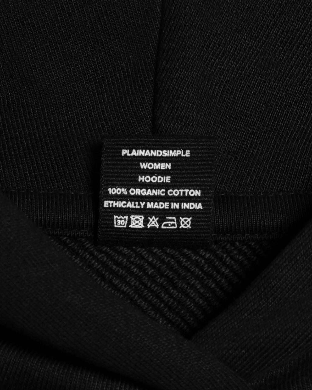 A close up of an neck label in a women's black heavyweight organic cotton hoodie.