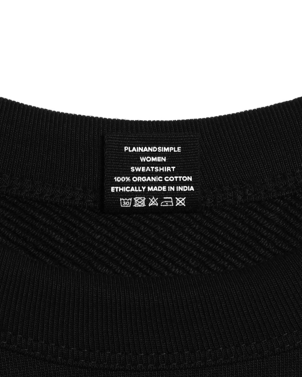 A close up of an neck label in a women's black heavyweight organic cotton sweatshirt.