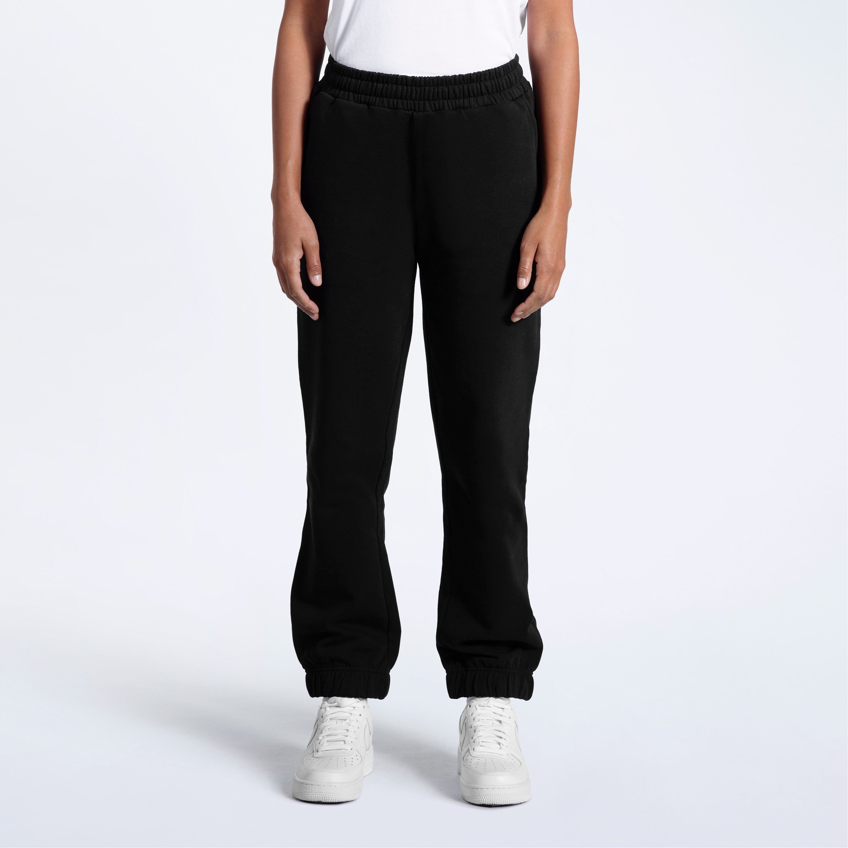 A person with their arms by their sides, modelling a pair of women's black heavyweight organic cotton joggers.