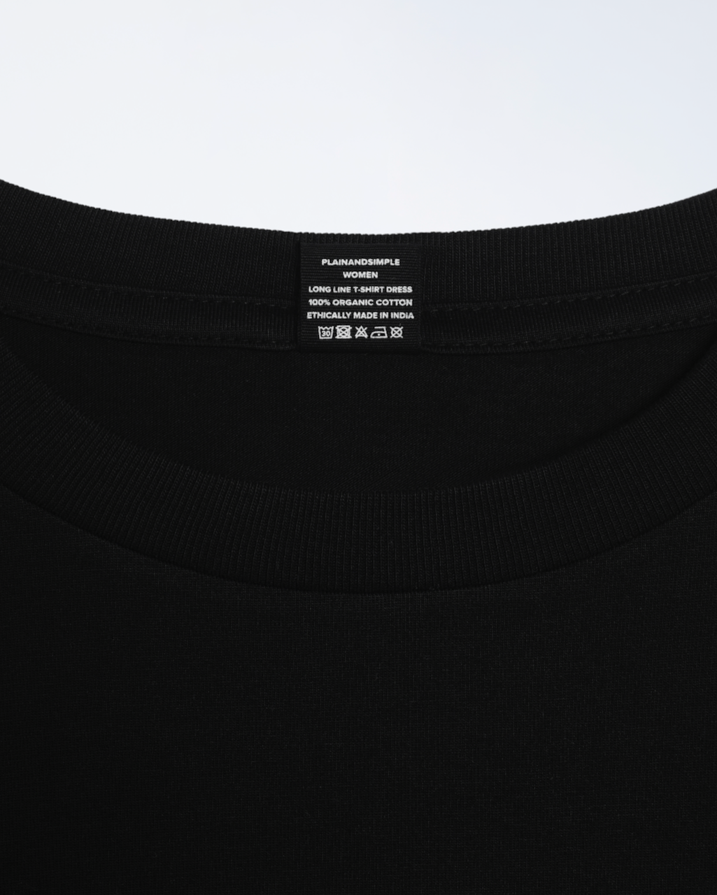 A close up of the nack label on a black, long line, organic cotton t shirt dress.