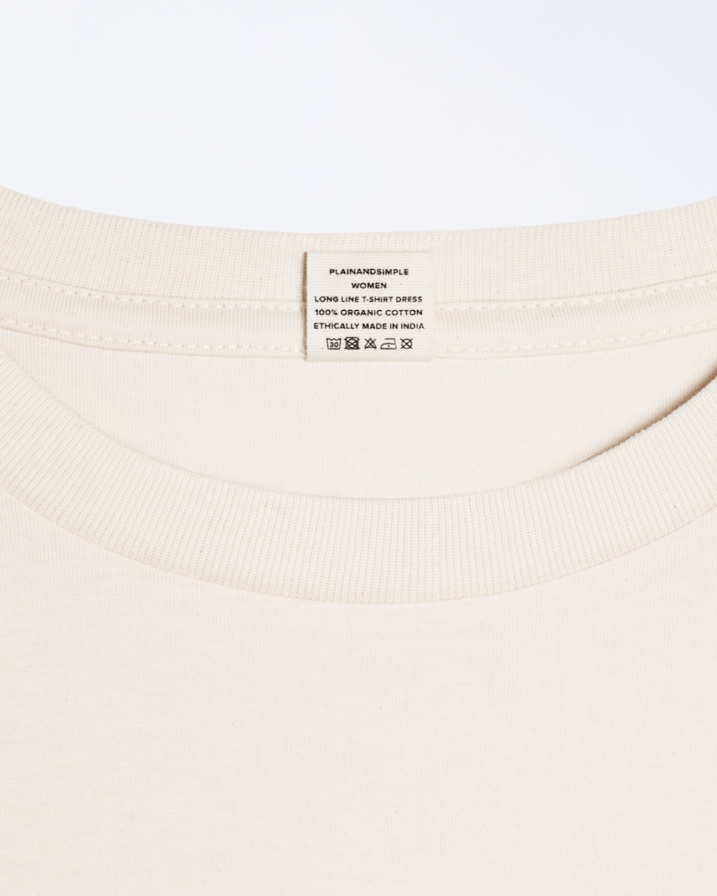 A close up of the nack label on a natural coloured, long line, organic cotton t shirt dress.