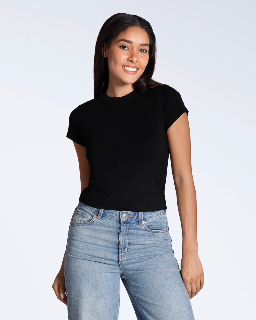 A woman smiling into the camera, modelling a plain black, organic cotton mini t shirt with a pair of blue jeans.