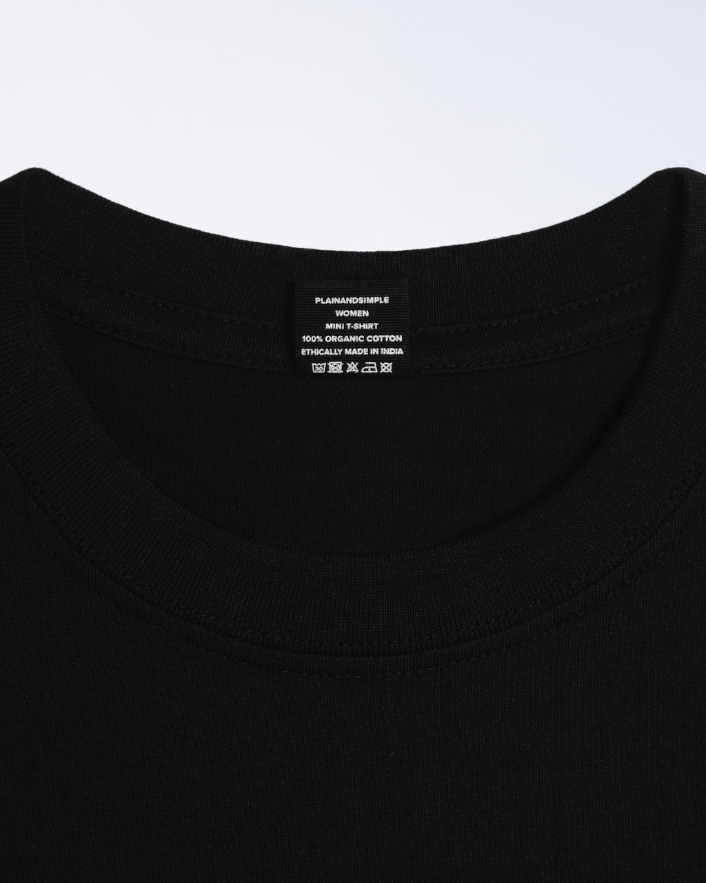 A close up of a neck label, for a black, organic cotton mini t shirt.