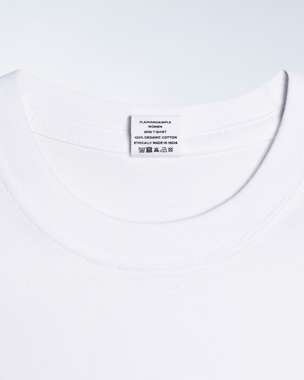 A close up of a neck label, for a white, organic cotton mini t shirt.