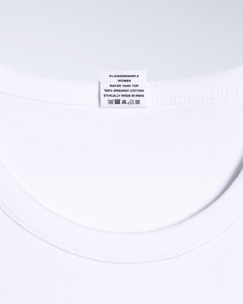 A close up of a neck label, for a white, organic cotton tank top.