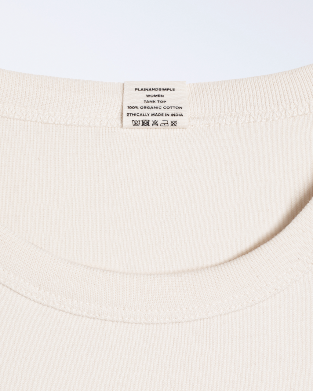 A close up of a neck label, for a natural coloured, organic cotton tank top.