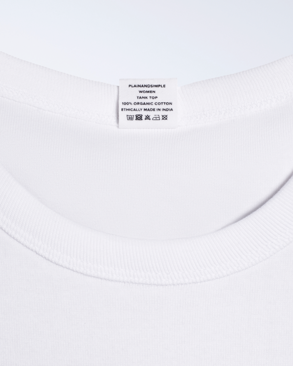 A close up of a neck label, for a white, organic cotton tank top.
