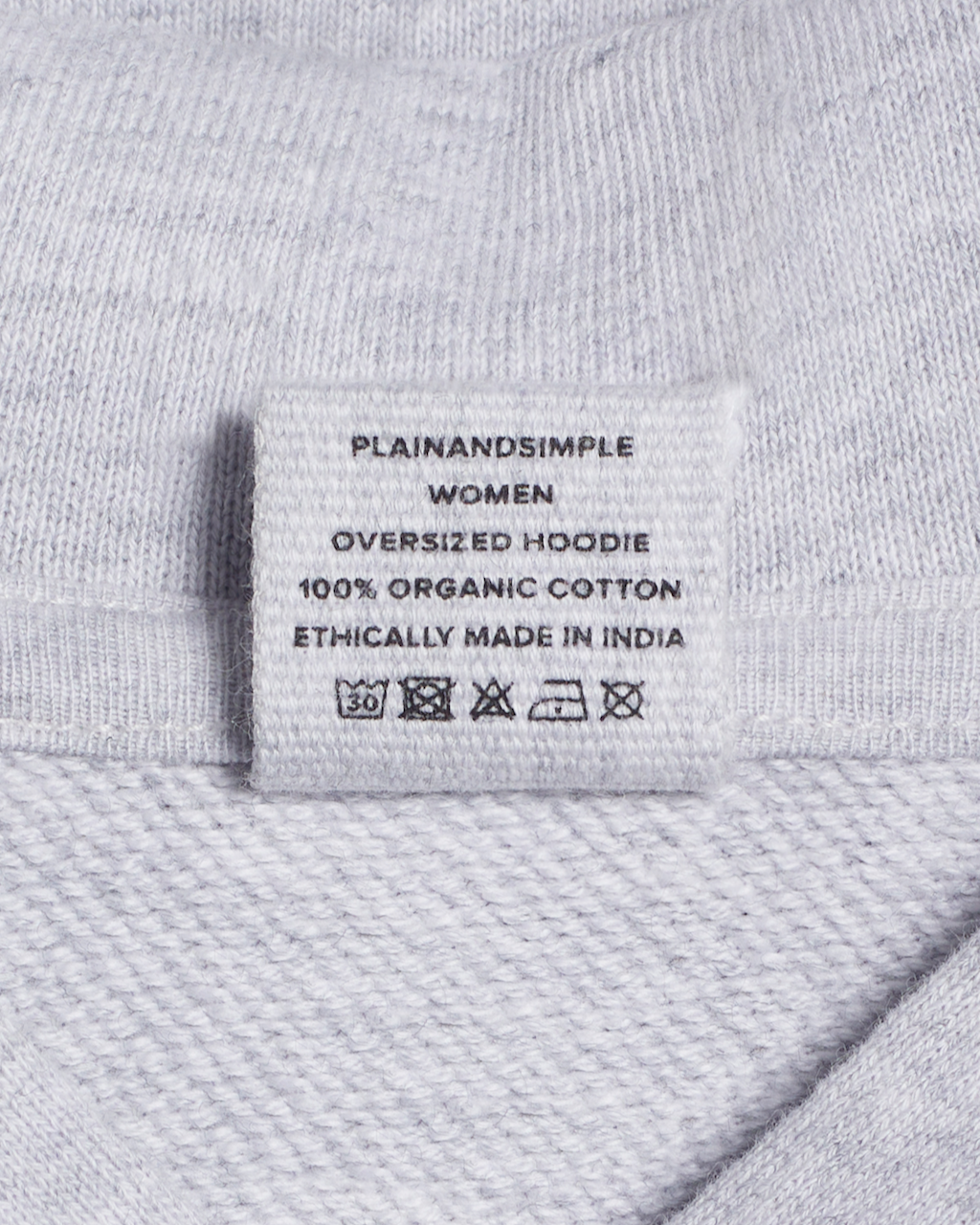 A close up of the neck label in a grey, oversized, organic cotton hoodie.