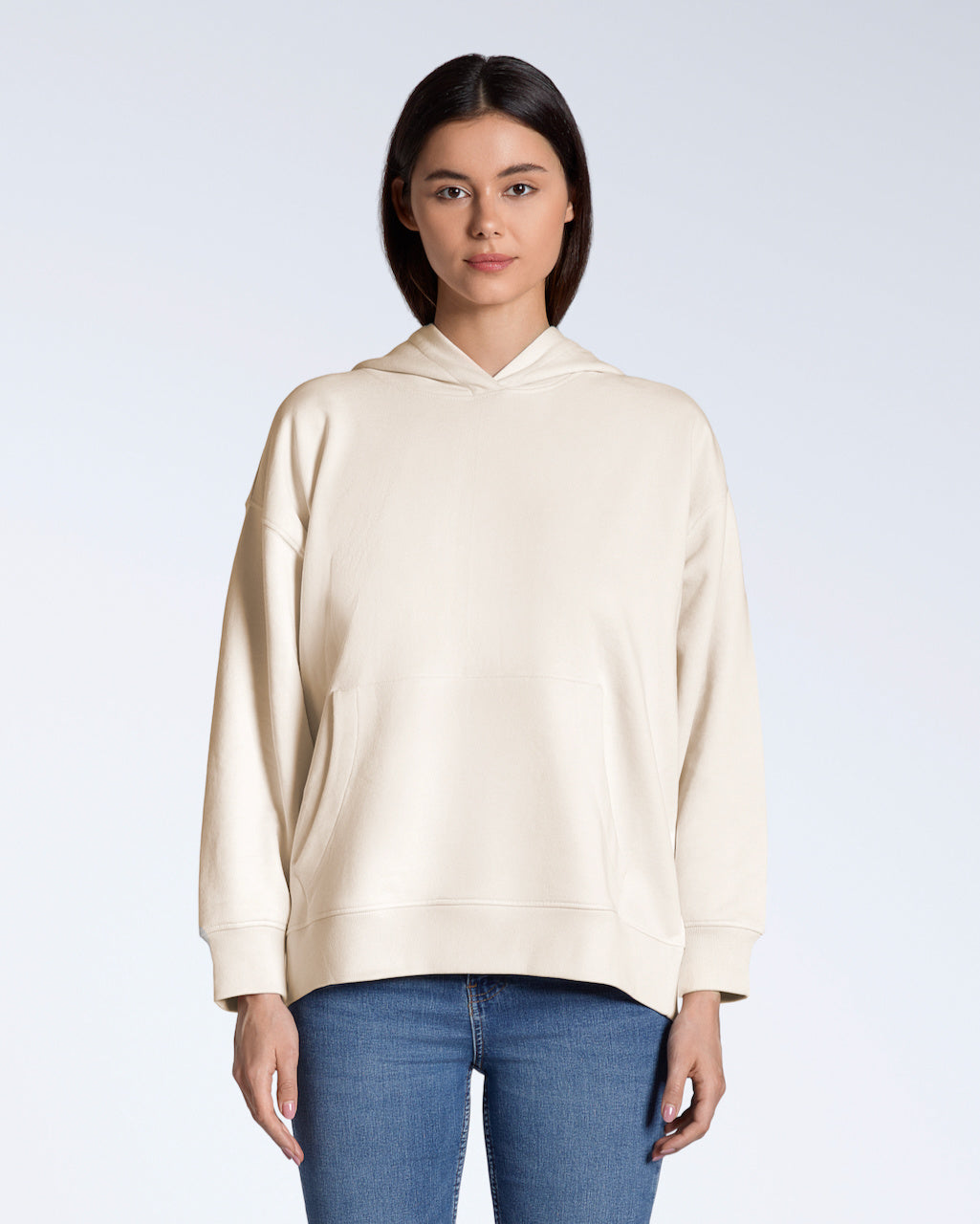 A woman facing front on, modelling a plain natural coloured, oversized, organic cotton hoodie.