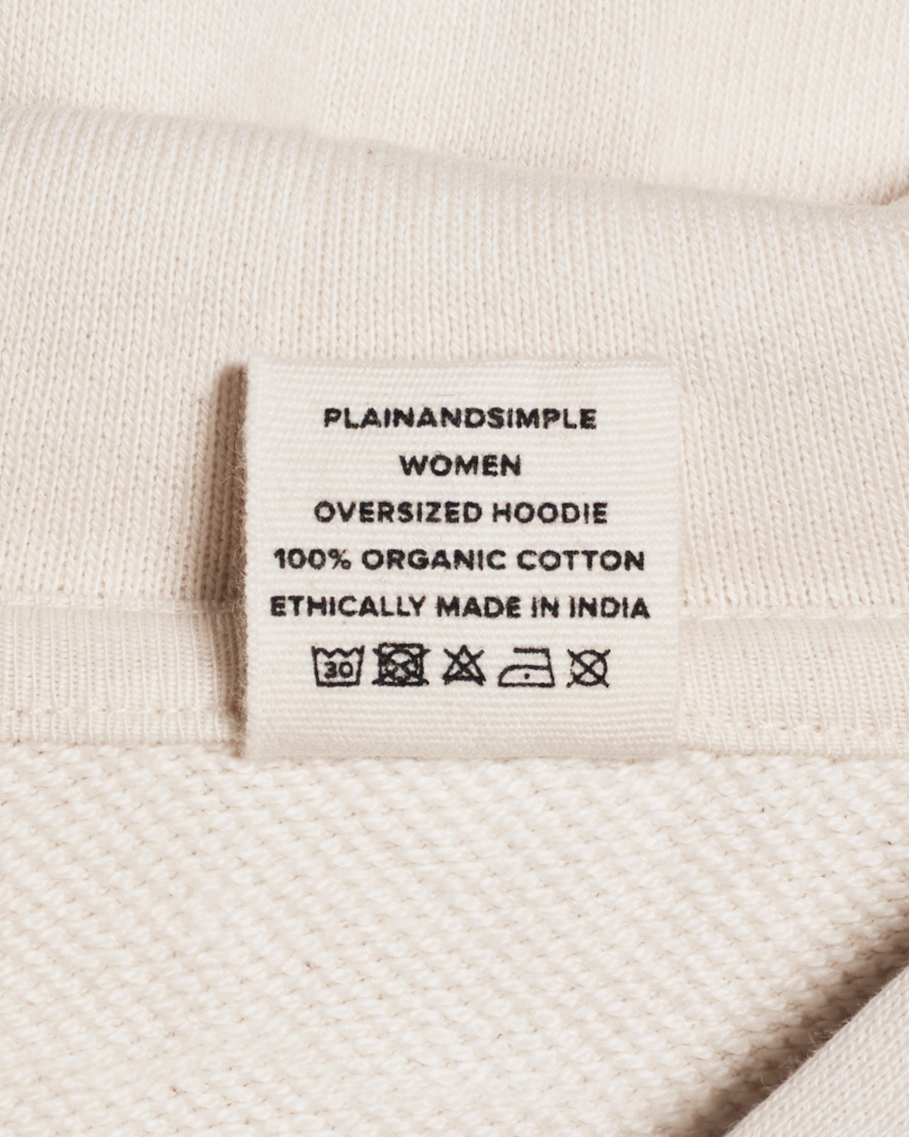 A close up of the neck label in a natural coloured, oversized, organic cotton hoodie.