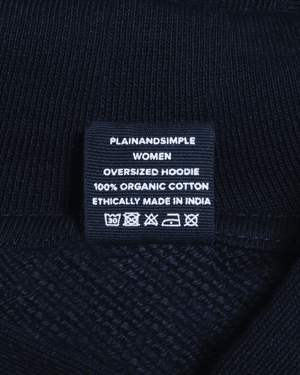 A close up of the neck label in a navy, oversized, organic cotton hoodie.