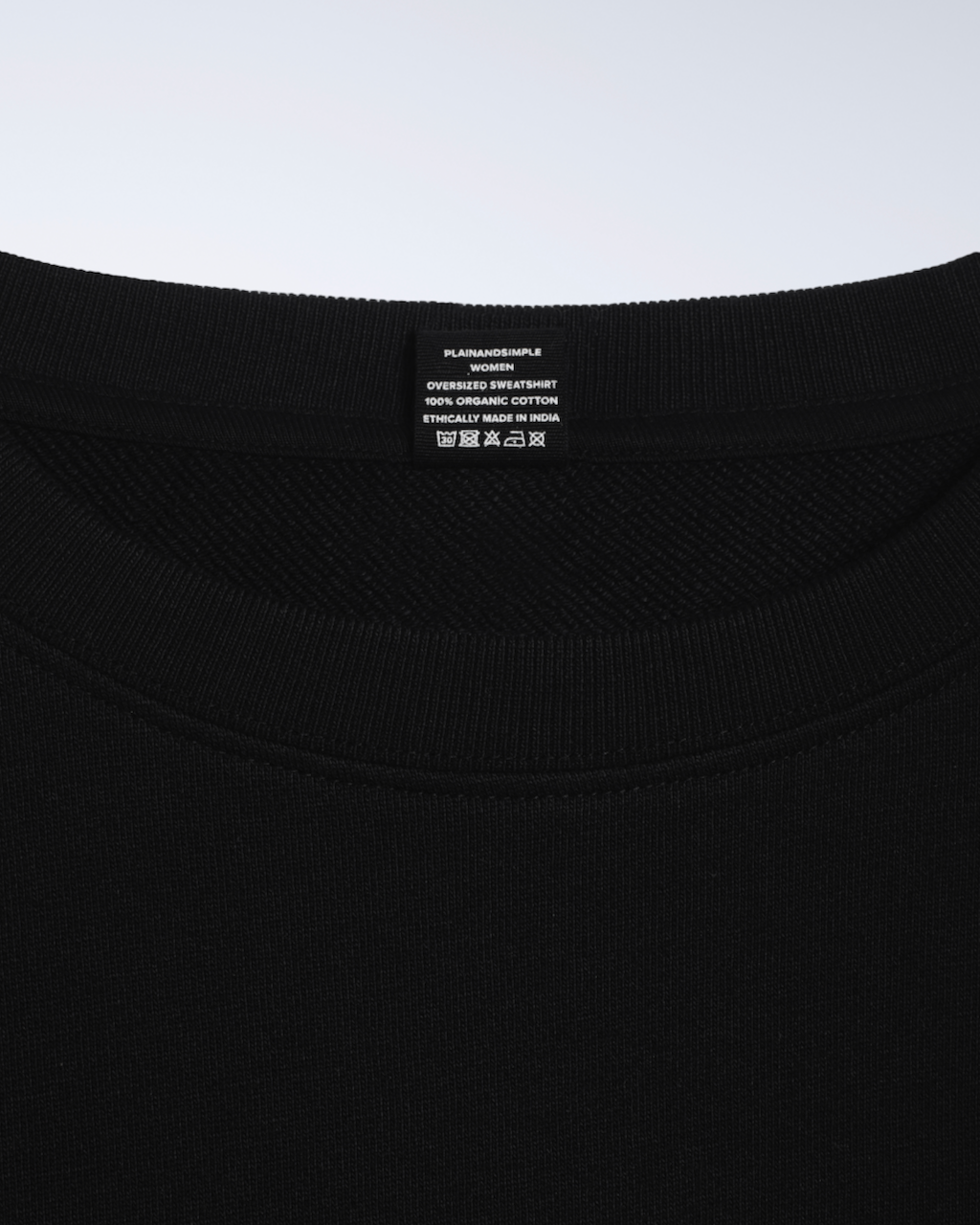 A close up of the neck label in a black, oversized, organic cotton sweatshirt.