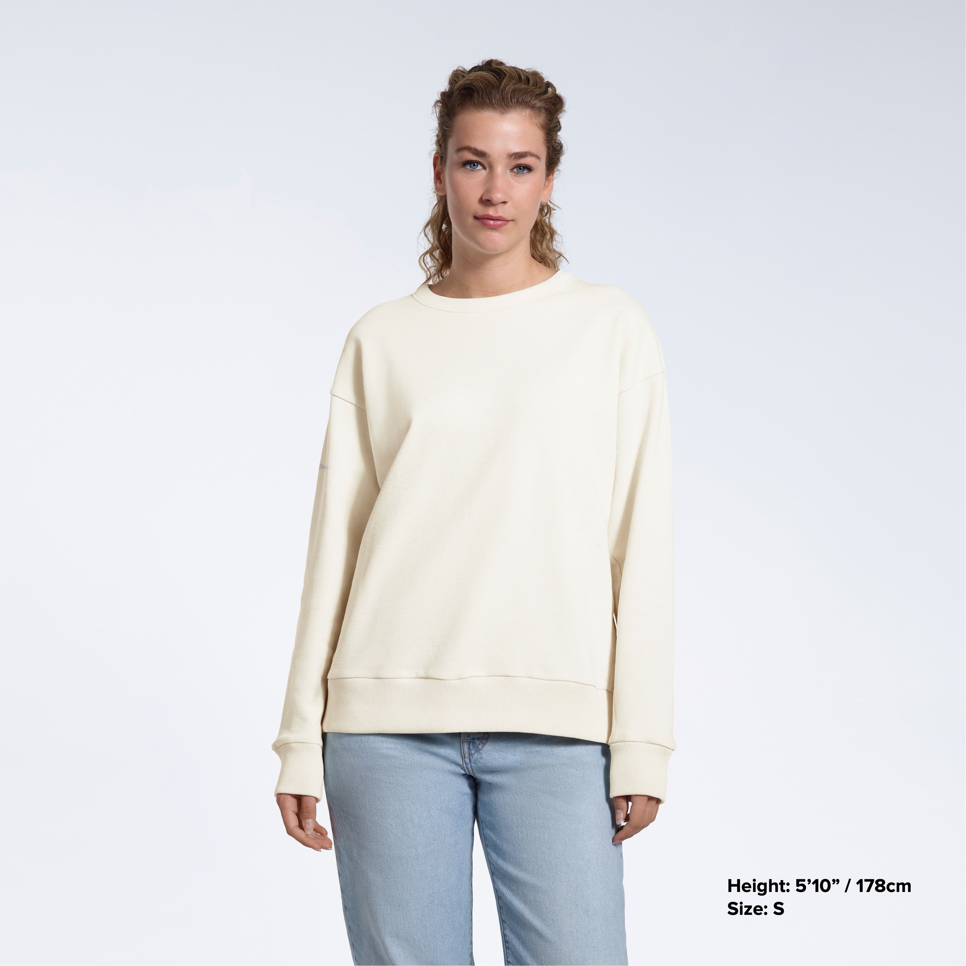 A woman looking into the camera with her arms by her side, modelling a plain ecru oversized organic cotton sweatshirt.