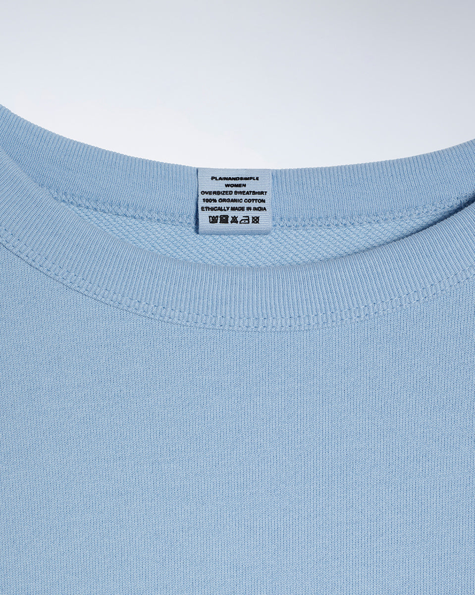 A close up of an neck label in a women's blue oversized organic cotton sweatshirt.