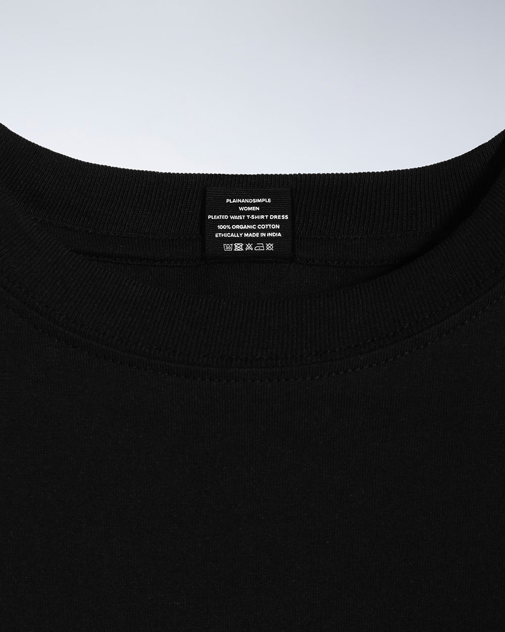 A close up of an neck label in a women's black organic cotton t shirt dress.
