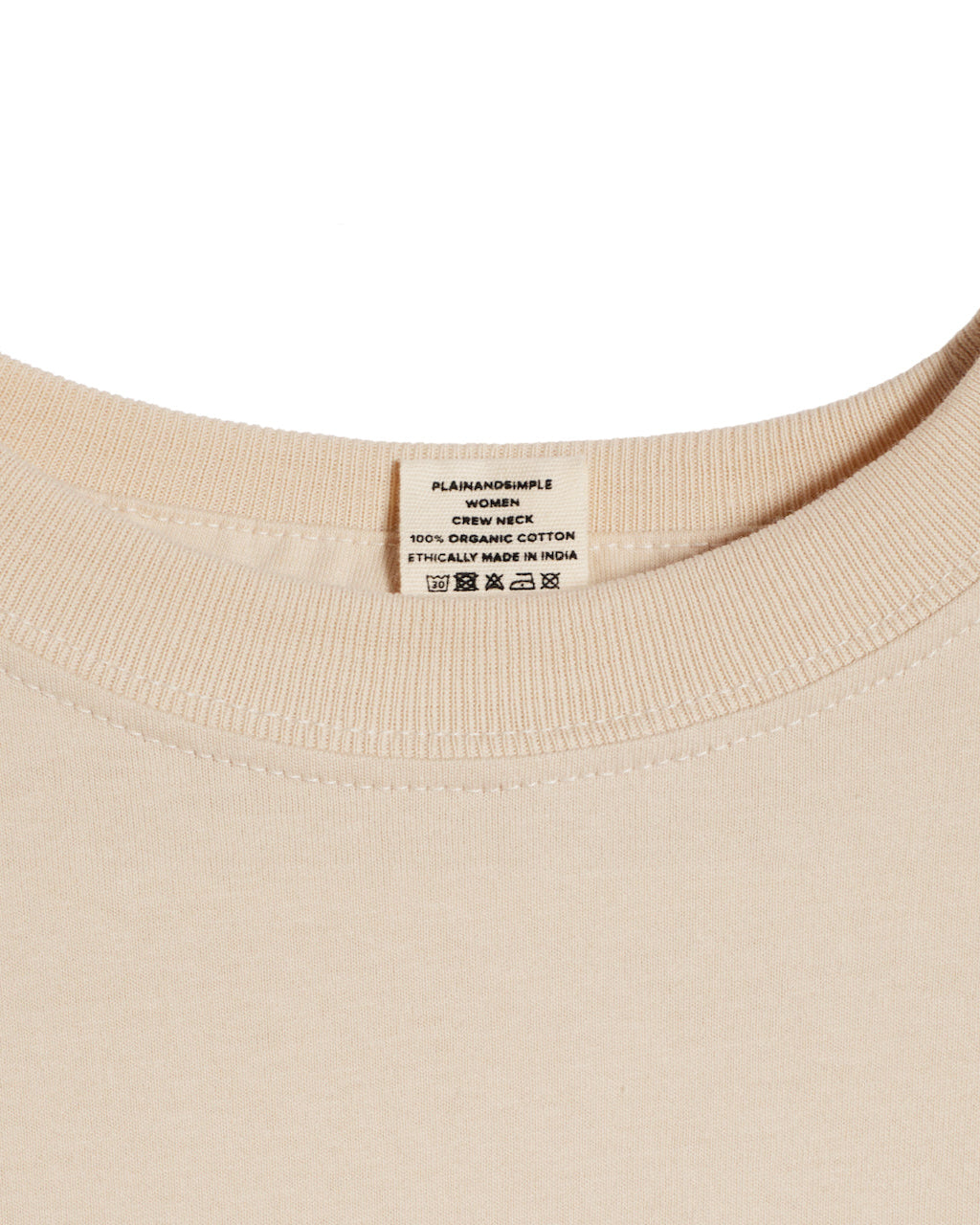 A close up of a neck label in a women's beige short sleeve crew neck organic cotton t shirt.