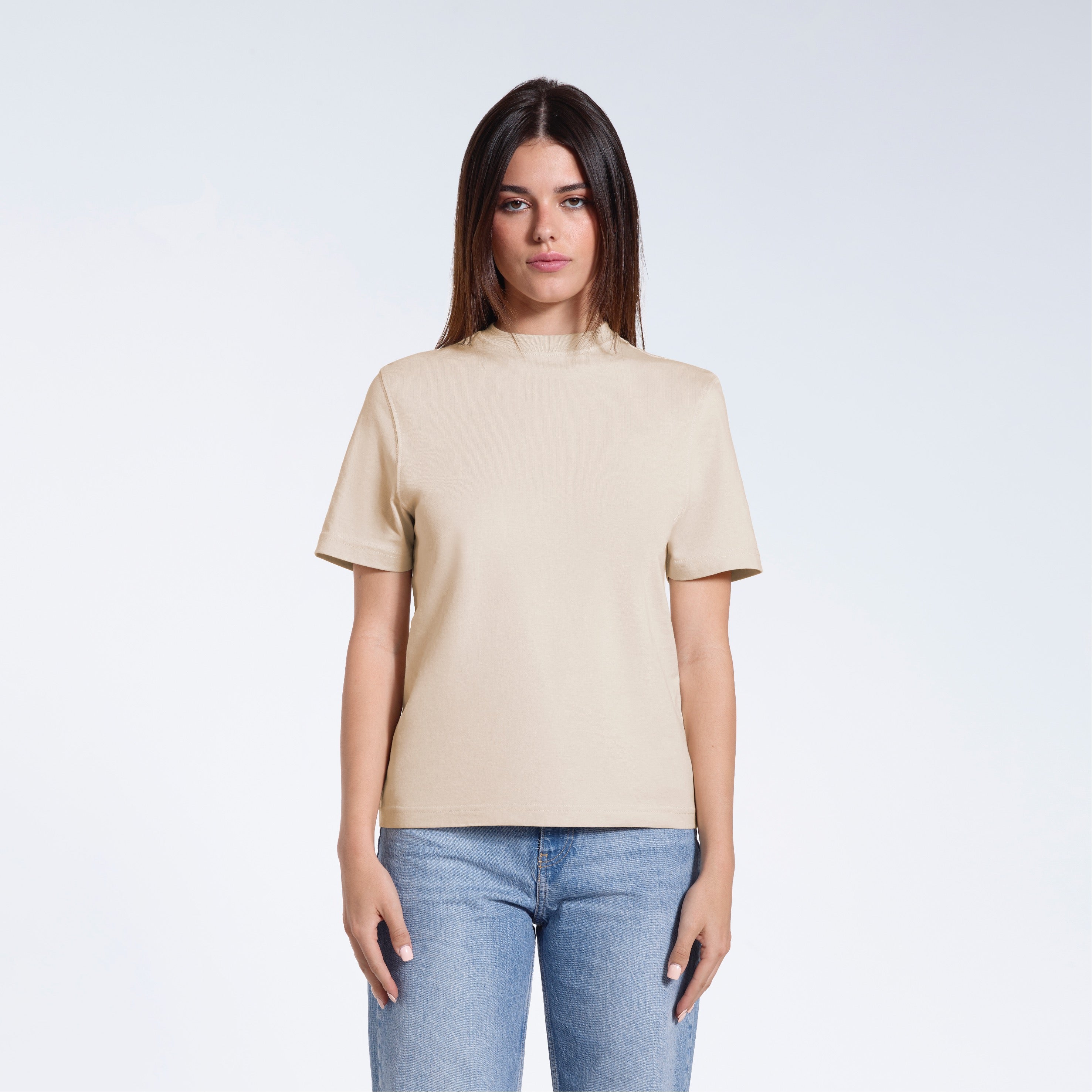 A woman facing front on looking at the camera, modelling a beige short sleeve organic cotton t shirt.