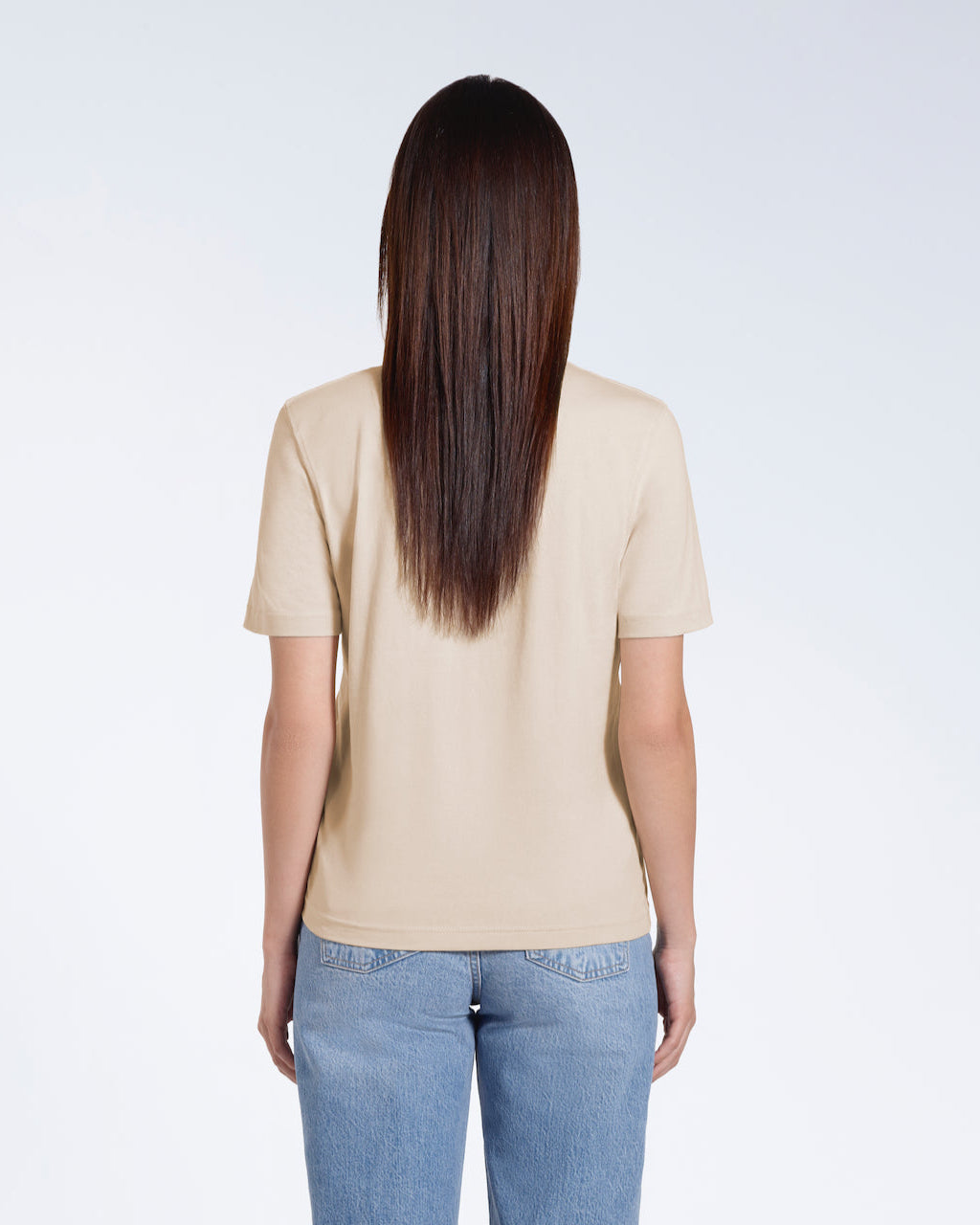 A woman with her back to the camera, modelling a plain beige short sleeve organic cotton t shirt.