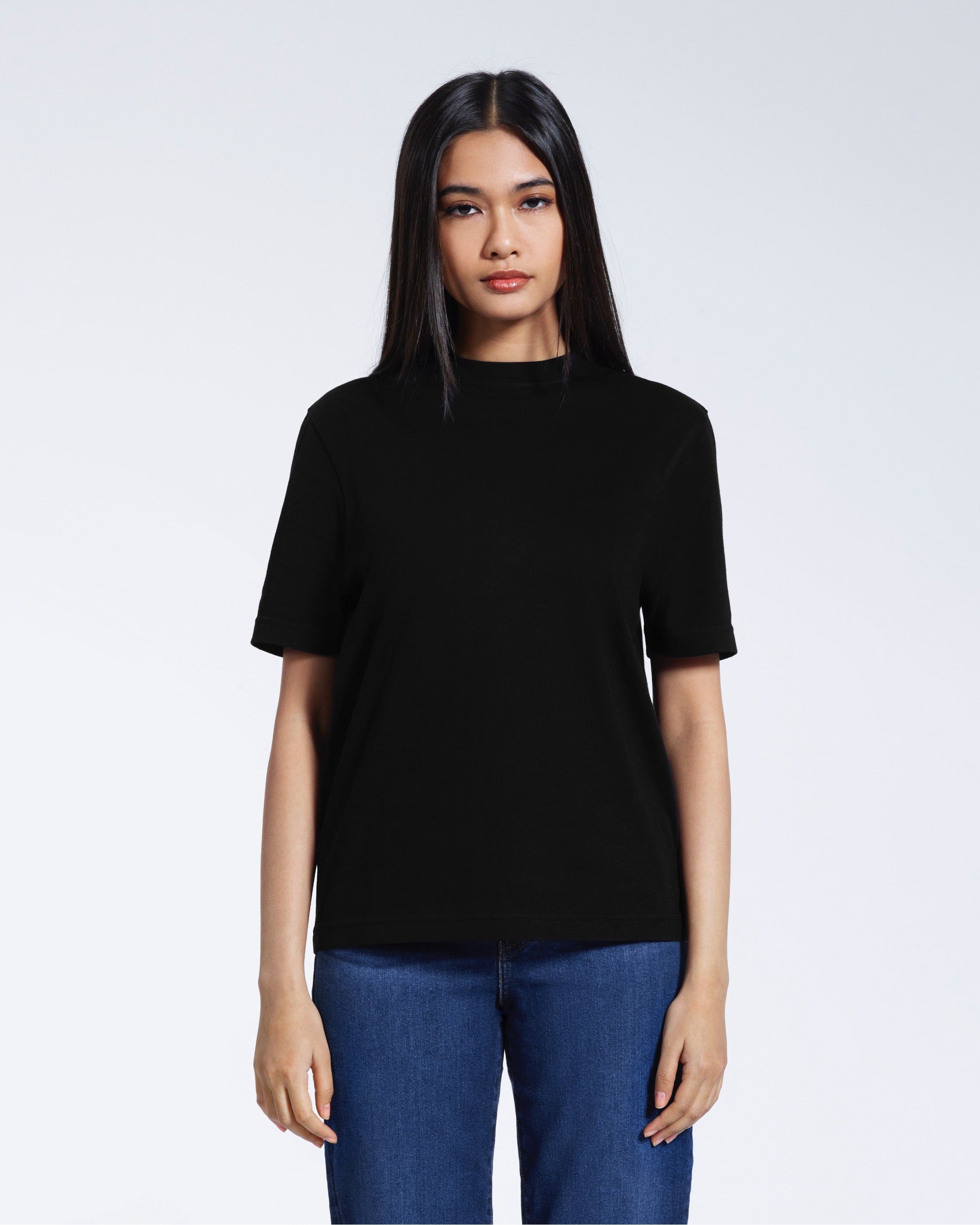 A woman facing front on looking at the camera, modelling a black short sleeve organic cotton t shirt.