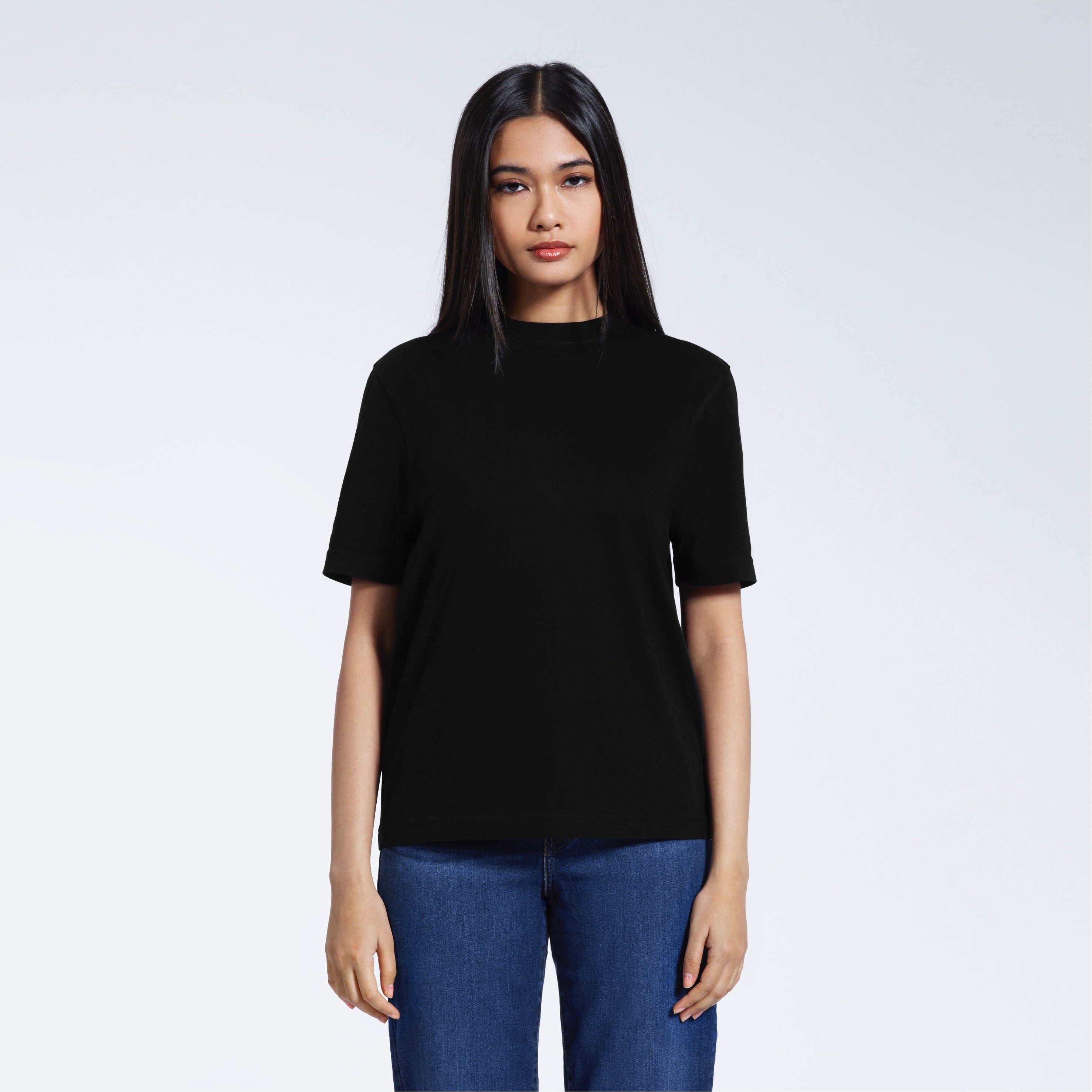 A woman facing front on looking at the camera, modelling a black short sleeve organic cotton t shirt.