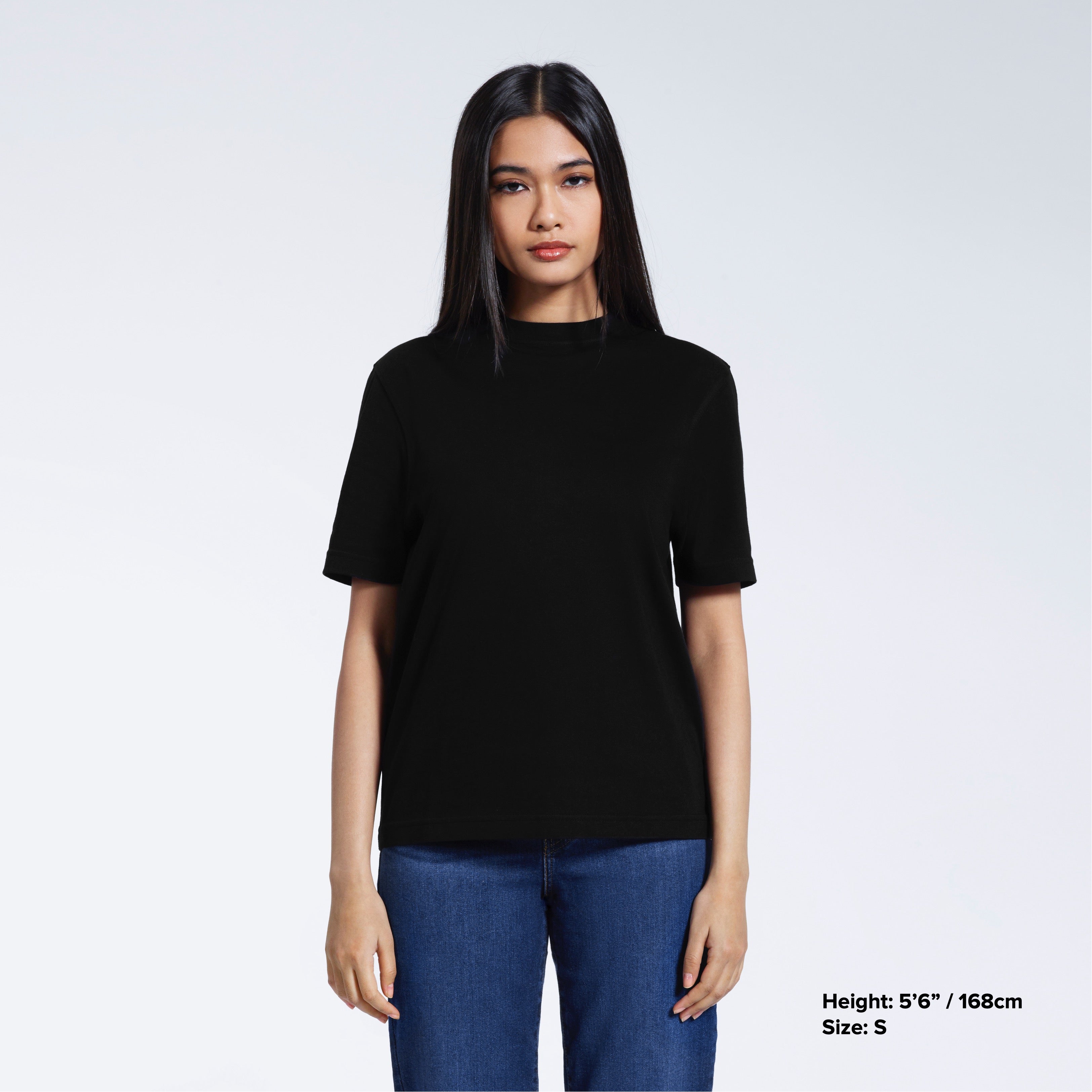 A woman facing front on looking at the camera, modelling a black short sleeve organic cotton t shirt.