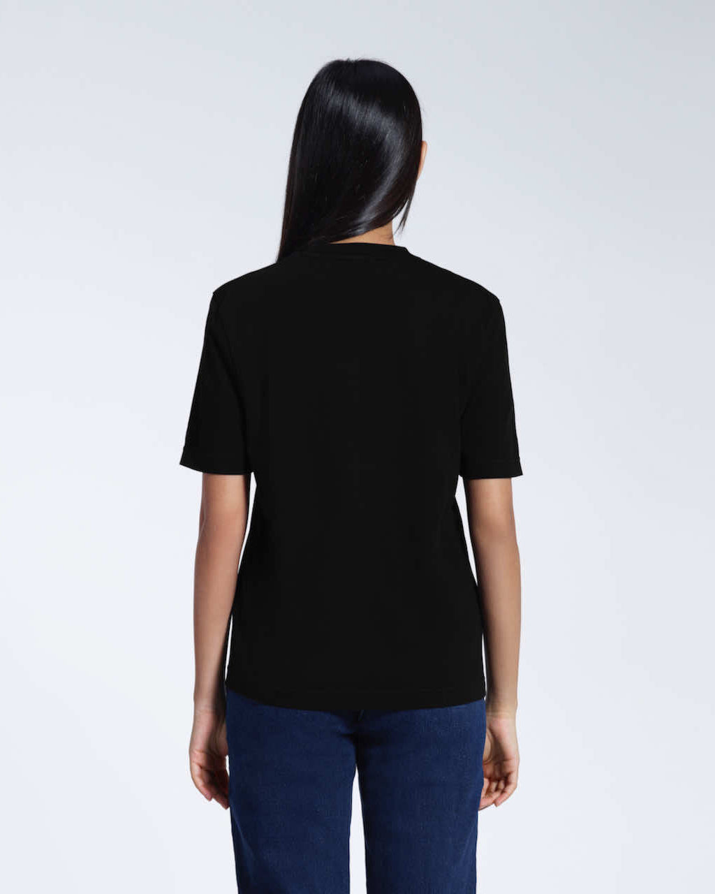 A woman with her back to the camera, modelling a plain black short sleeve organic cotton t shirt.