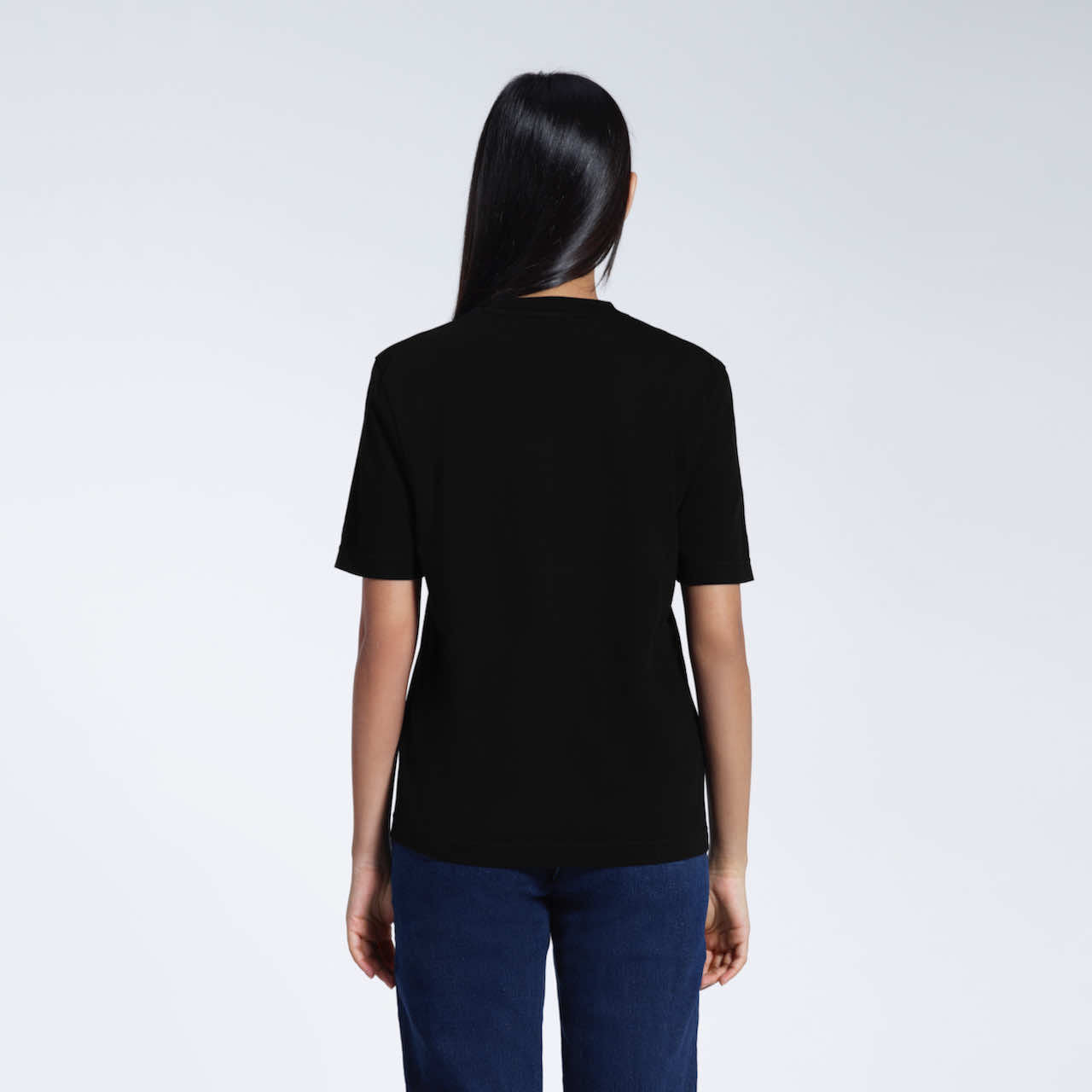 A woman with her back to the camera, modelling a plain black short sleeve organic cotton t shirt.