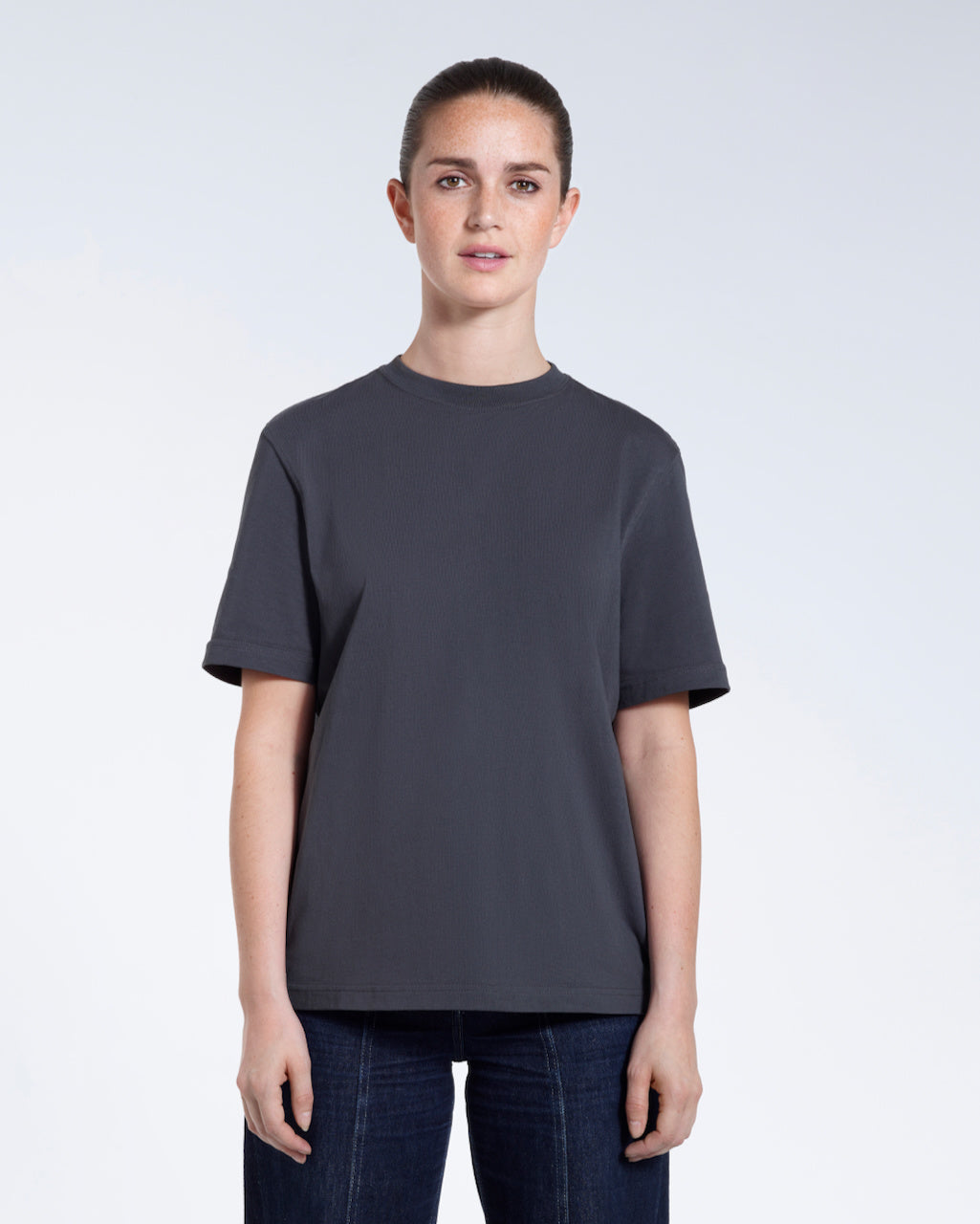 A woman facing front on looking at the camera, modelling a dark grey short sleeve organic cotton t shirt.