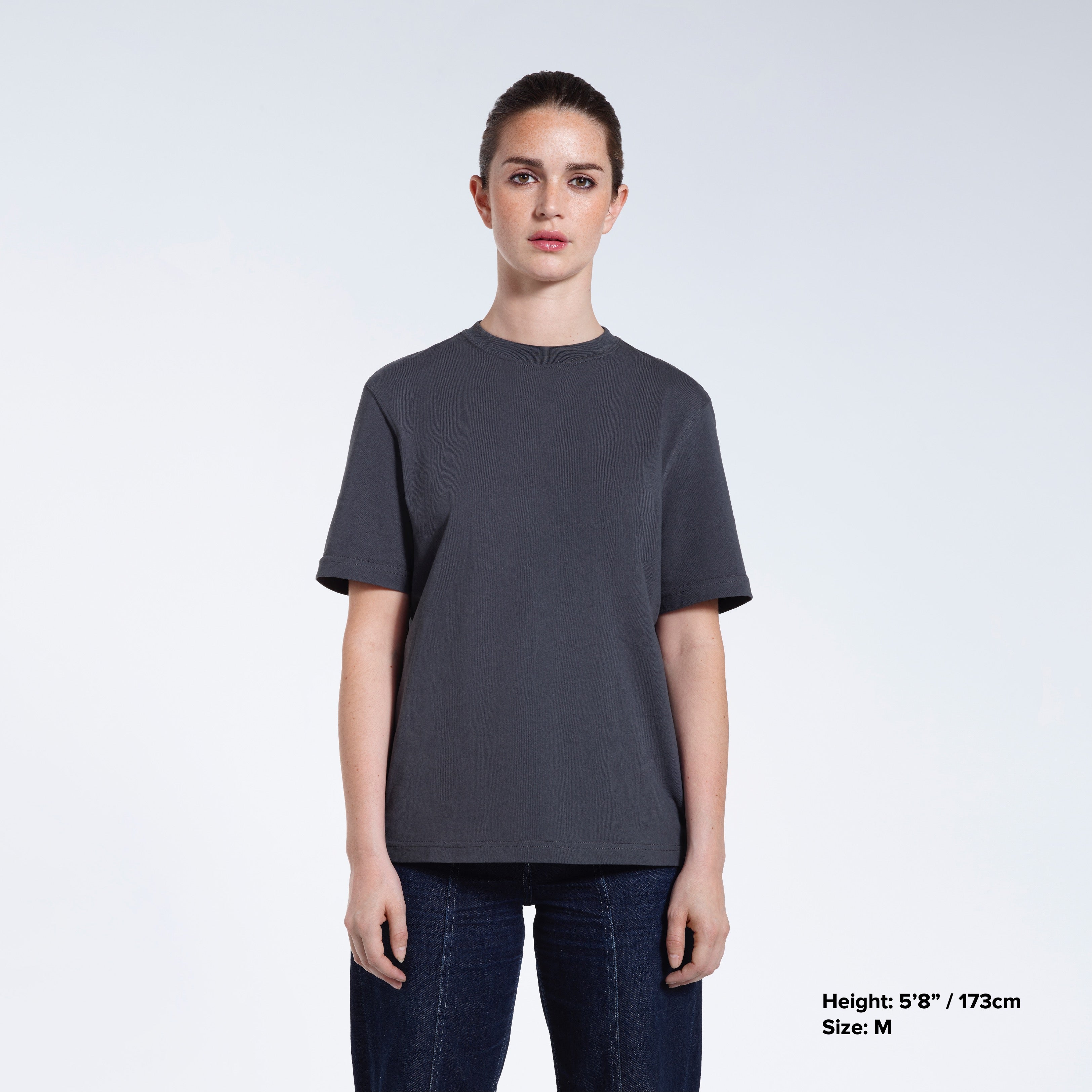 A woman facing front on looking at the camera, modelling a dark grey short sleeve organic cotton t shirt.