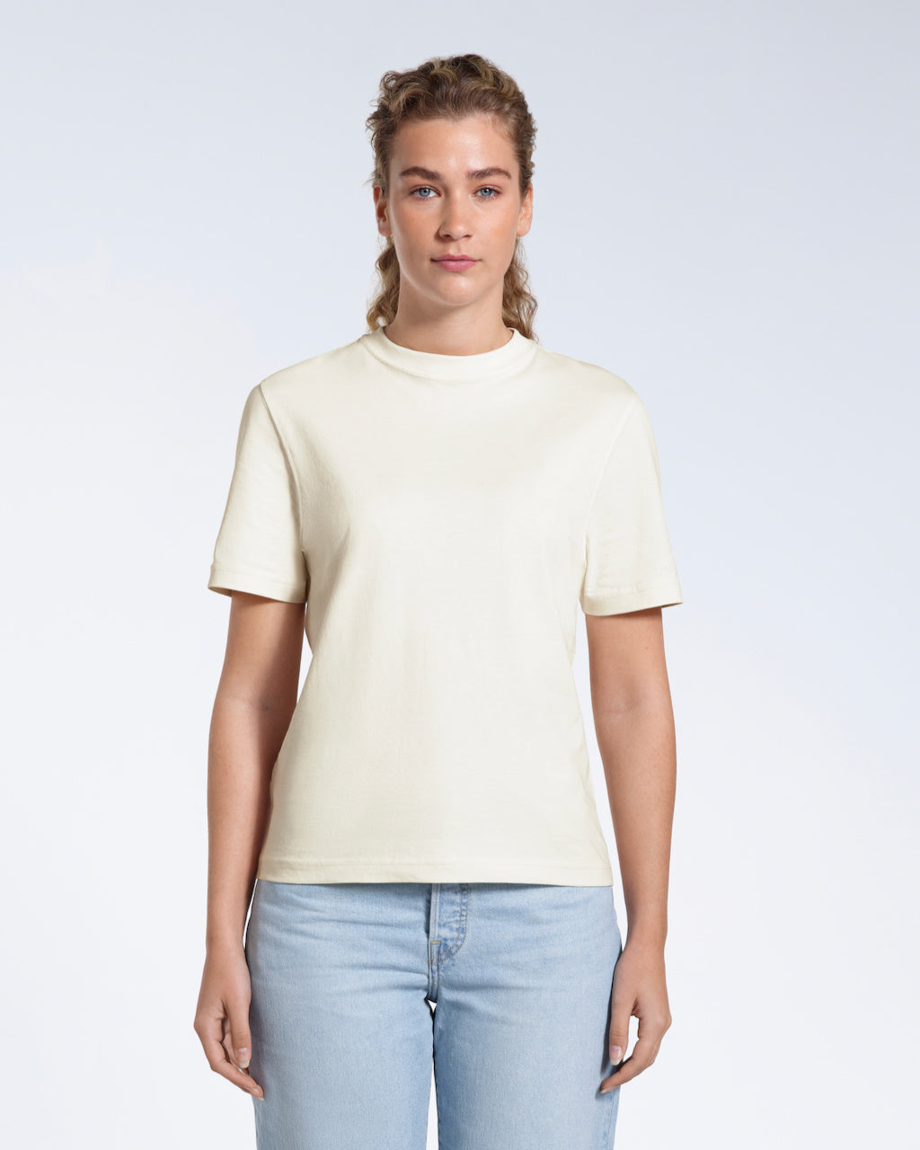 A woman facing front on looking at the camera, modelling an ecru short sleeve organic cotton t shirt.