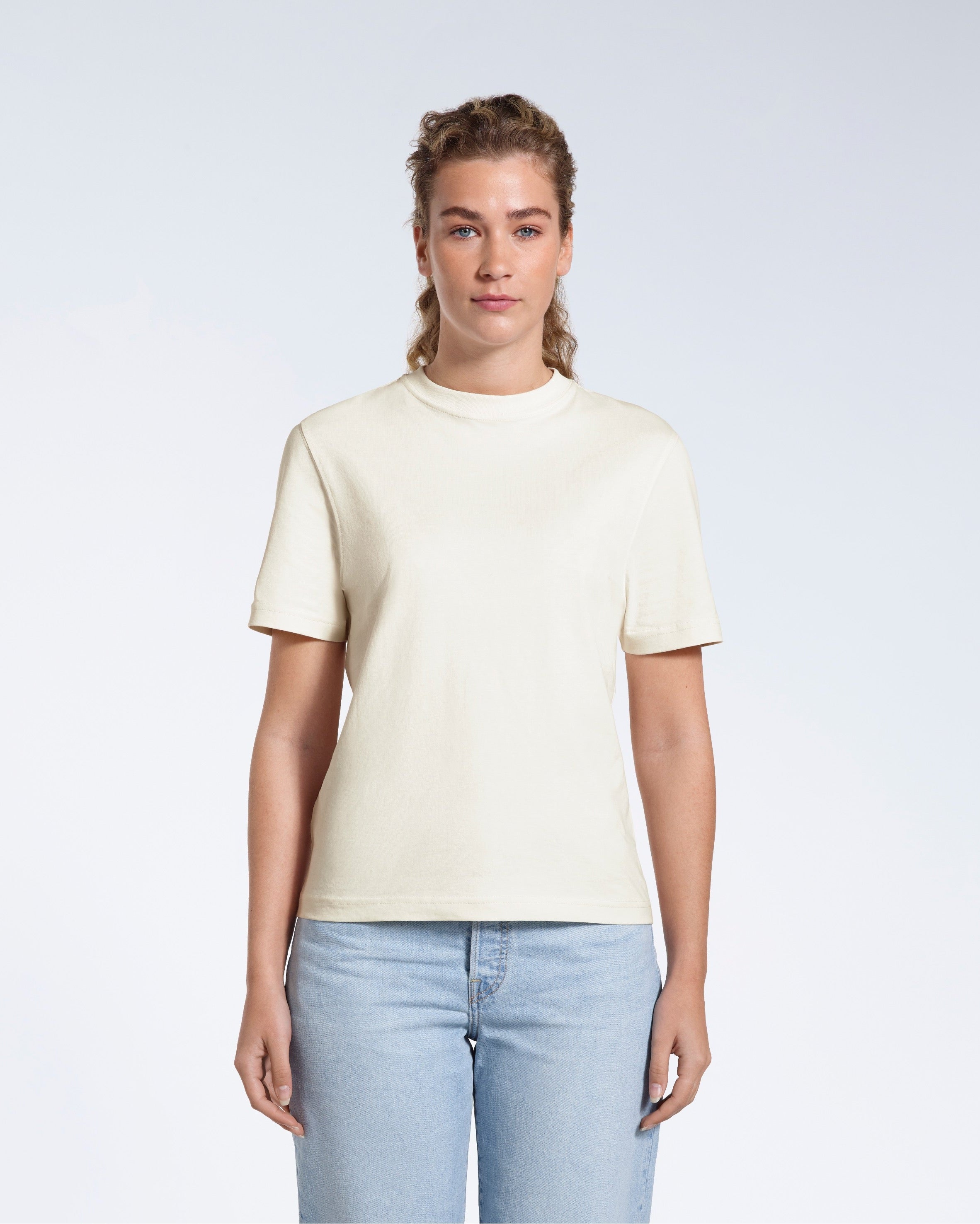 A woman facing front on looking at the camera, modelling an ecru short sleeve organic cotton t shirt.