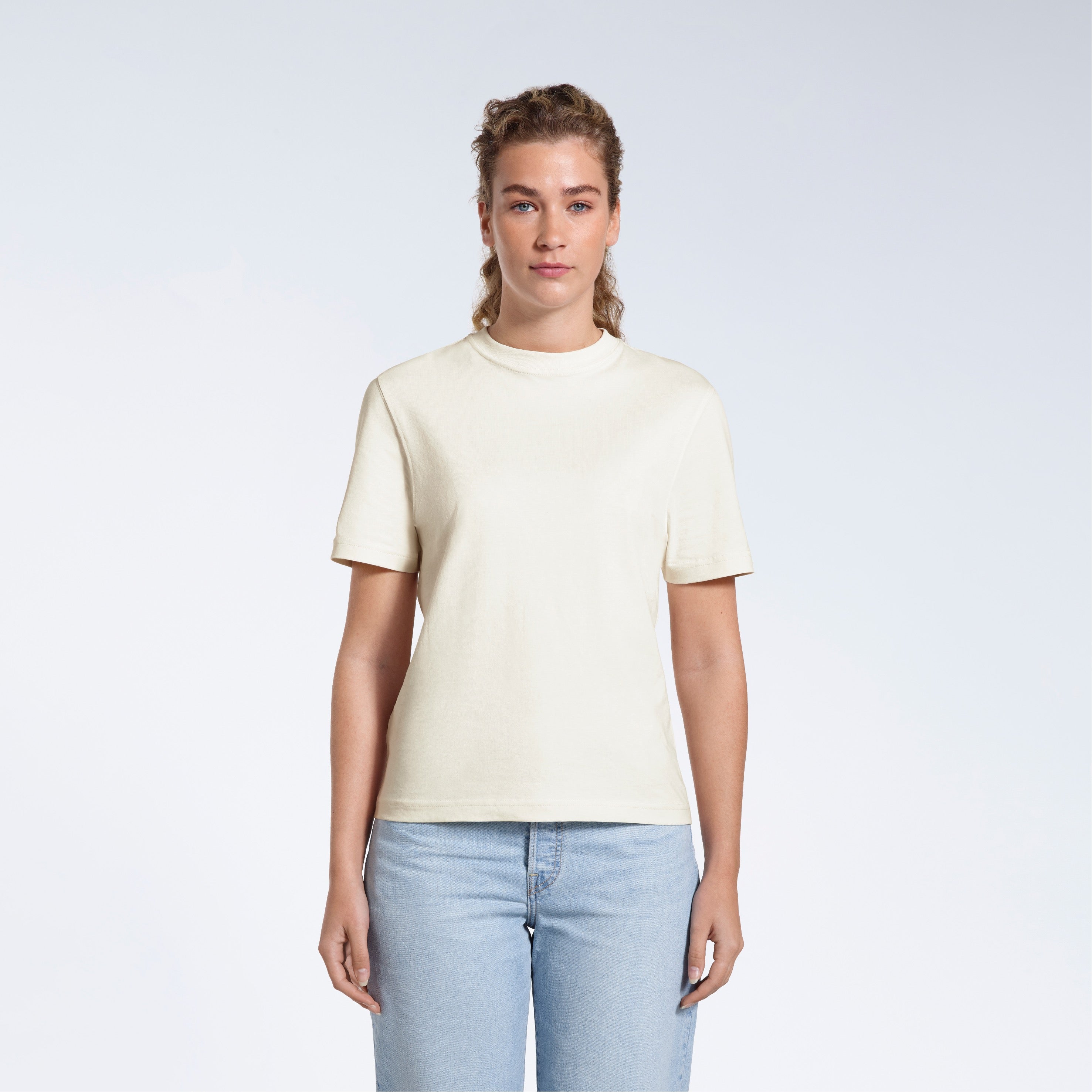 A woman facing front on looking at the camera, modelling an ecru short sleeve organic cotton t shirt.